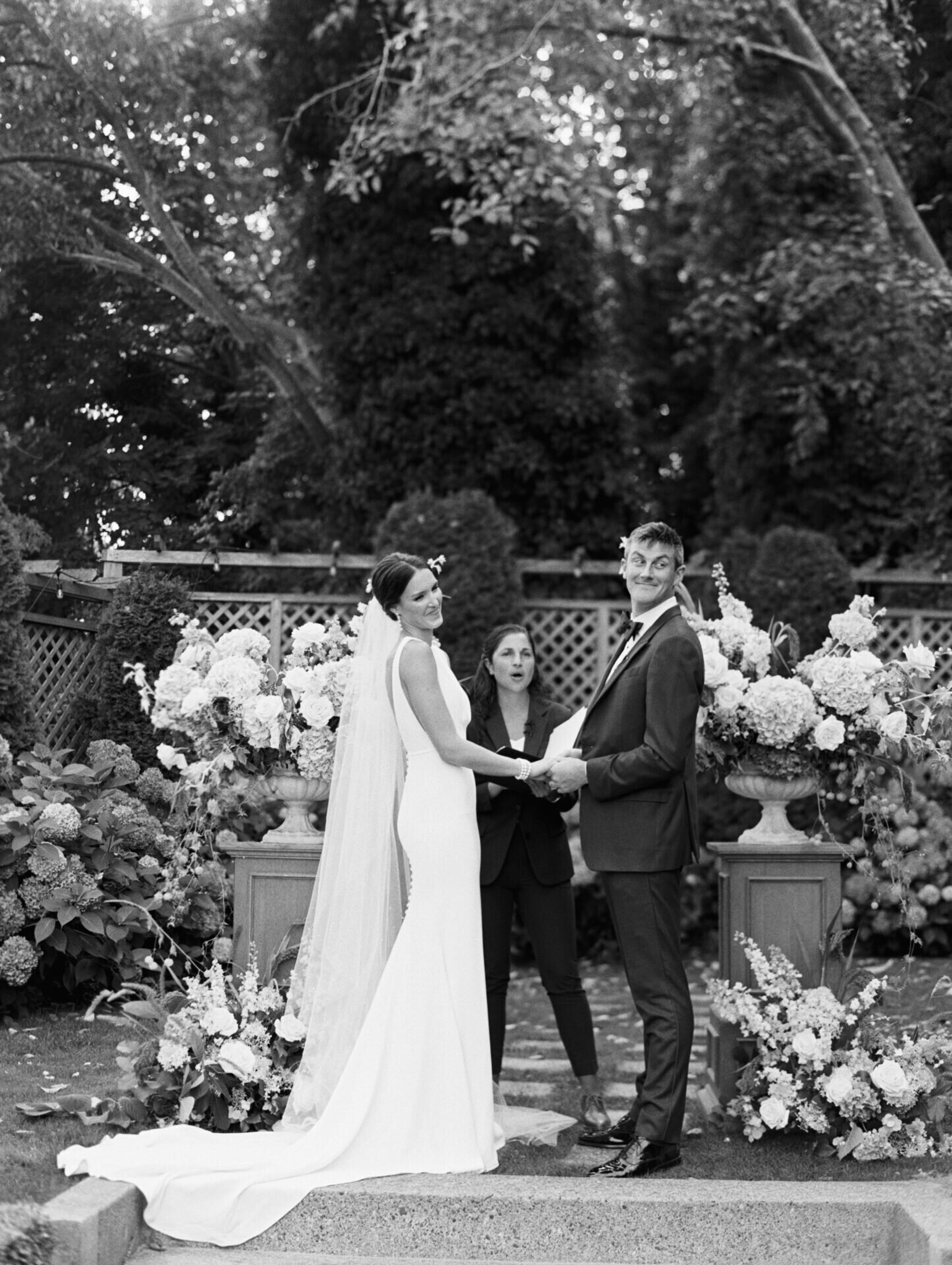 black and white film photo of bride and groom holding hands at wedding ceremony