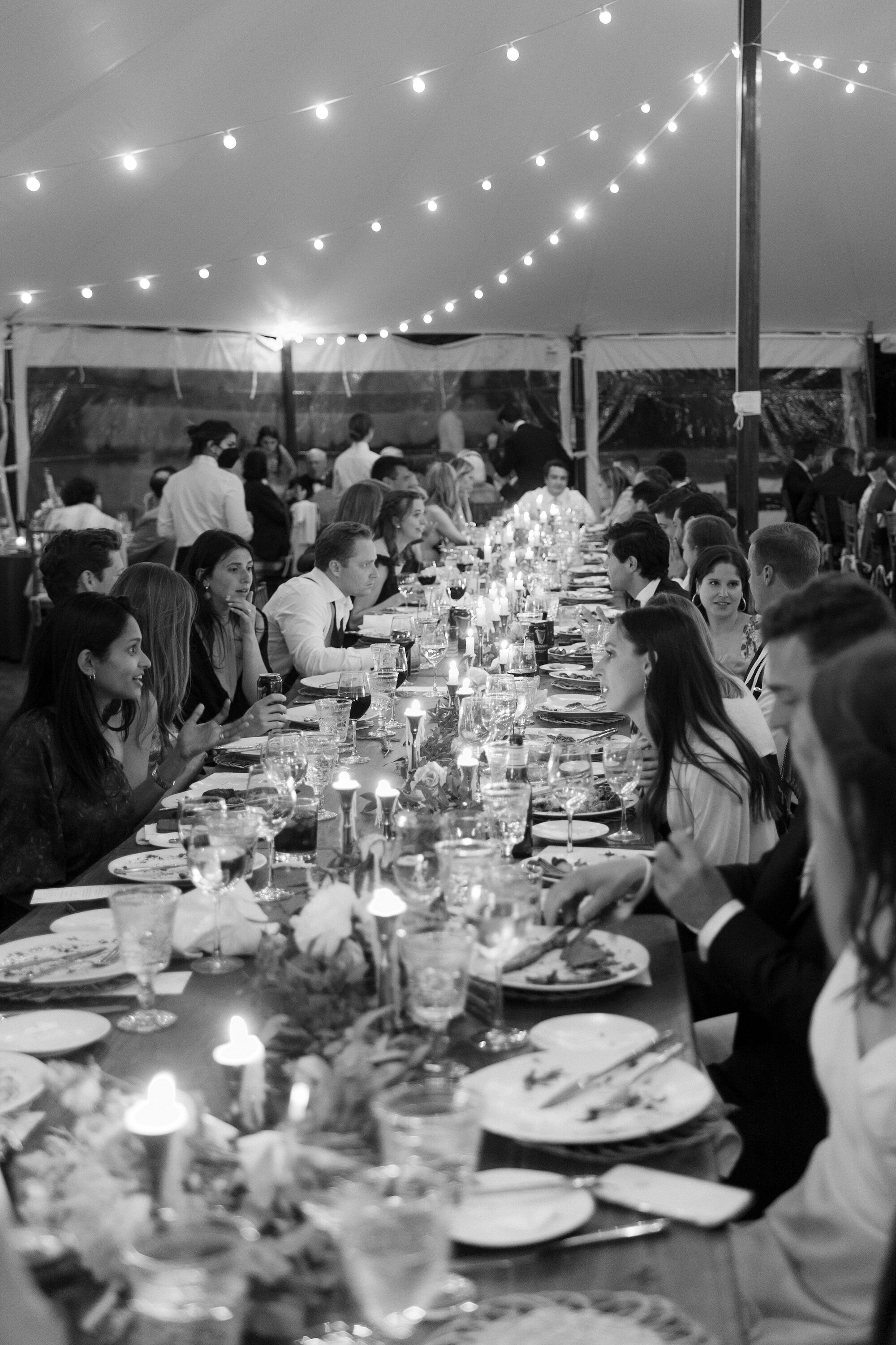 guests enjoy dinner at tented wedding by candlelight in black and white in the Catskills