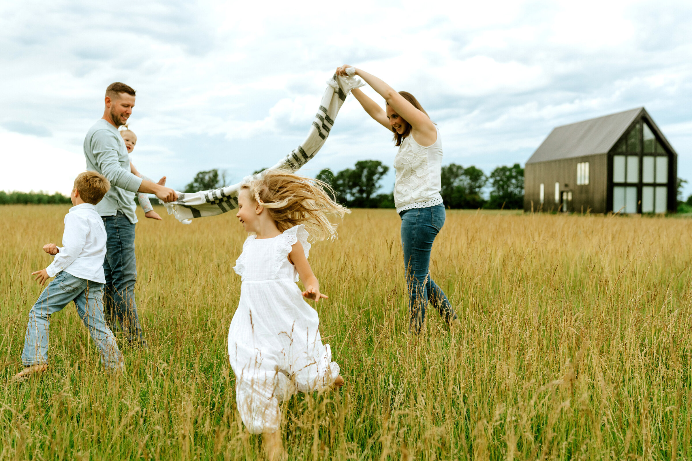 Family of six playing in front of house with windows