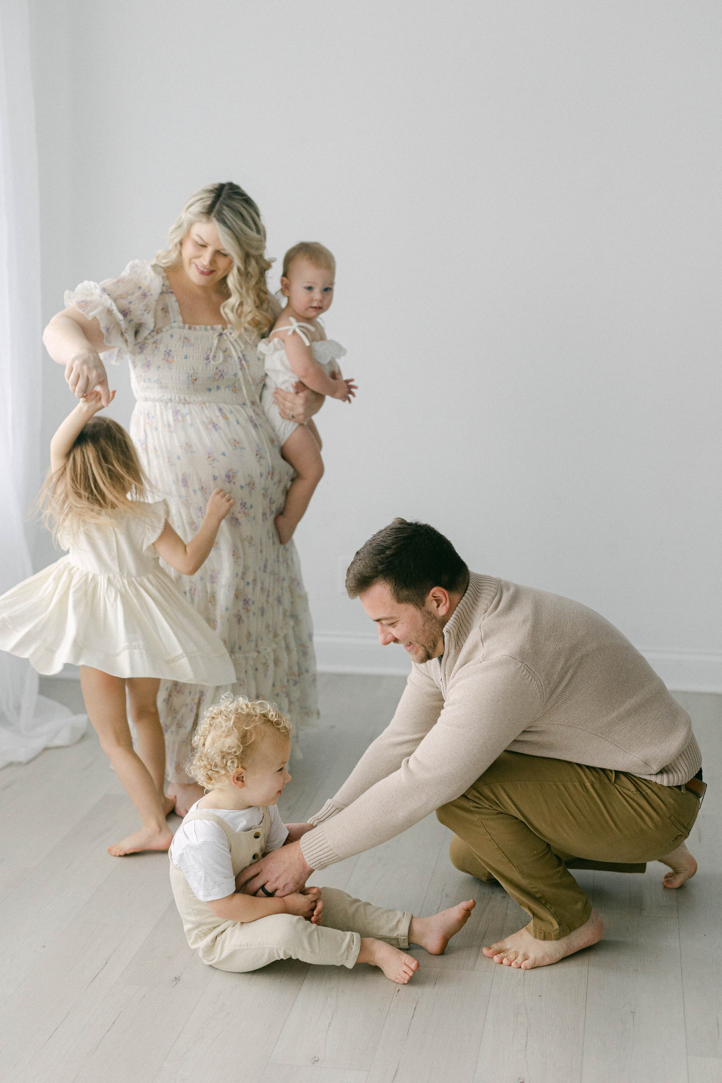 family playing in photography studio with little girl twirling with mom and dad tickling his son  knoxville tennessee newborn photographer