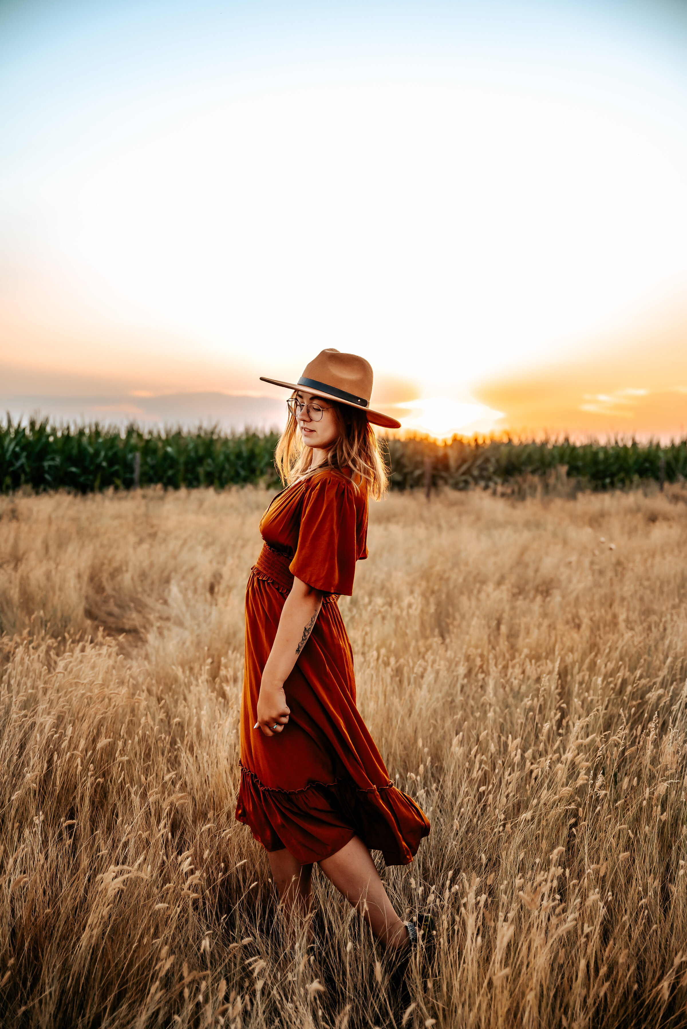 Girl spins in field in orange dress with hat on