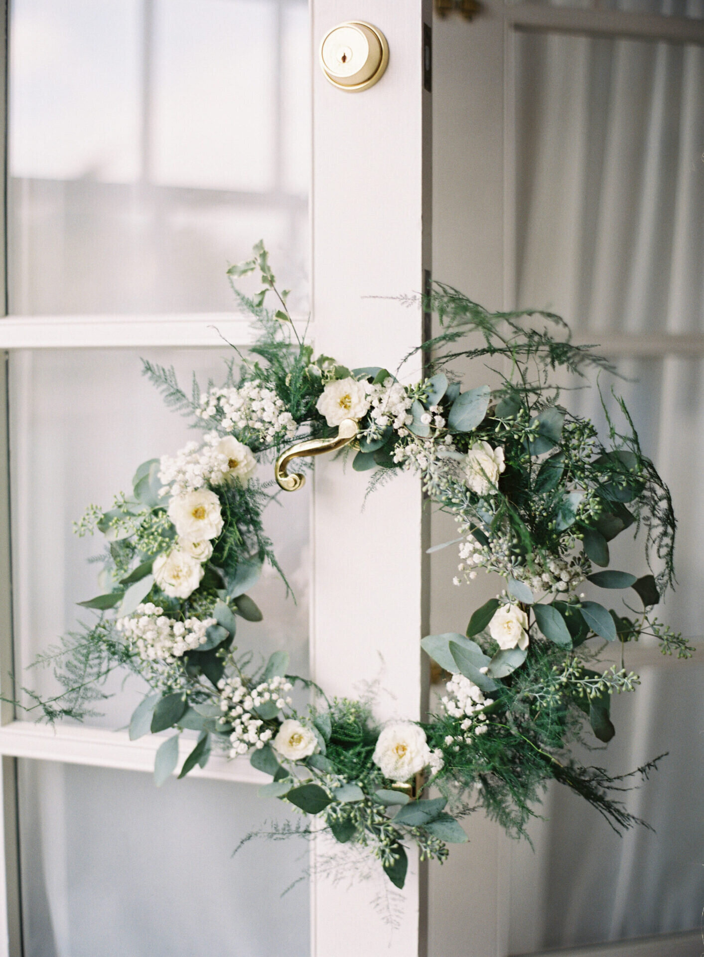 green and white floral wreath hangin on golden door knob at seattle tennis club wedding