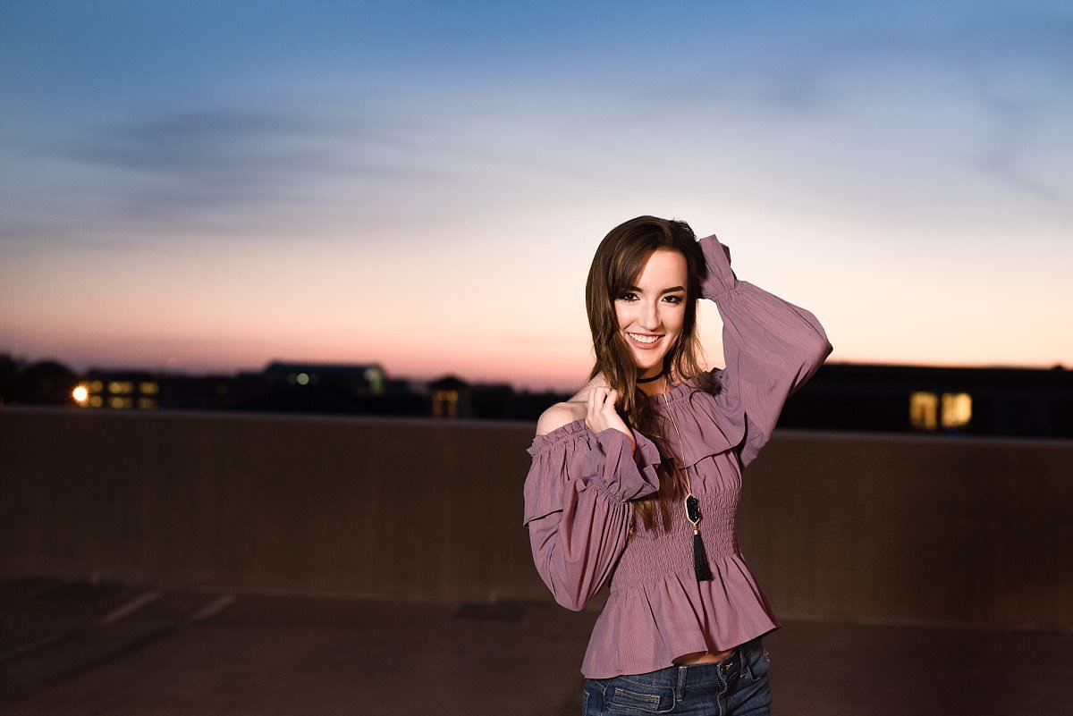 Senior wearing clothing styled by Hello Beautiful and standing on top of parking garage at MTSU during sunset