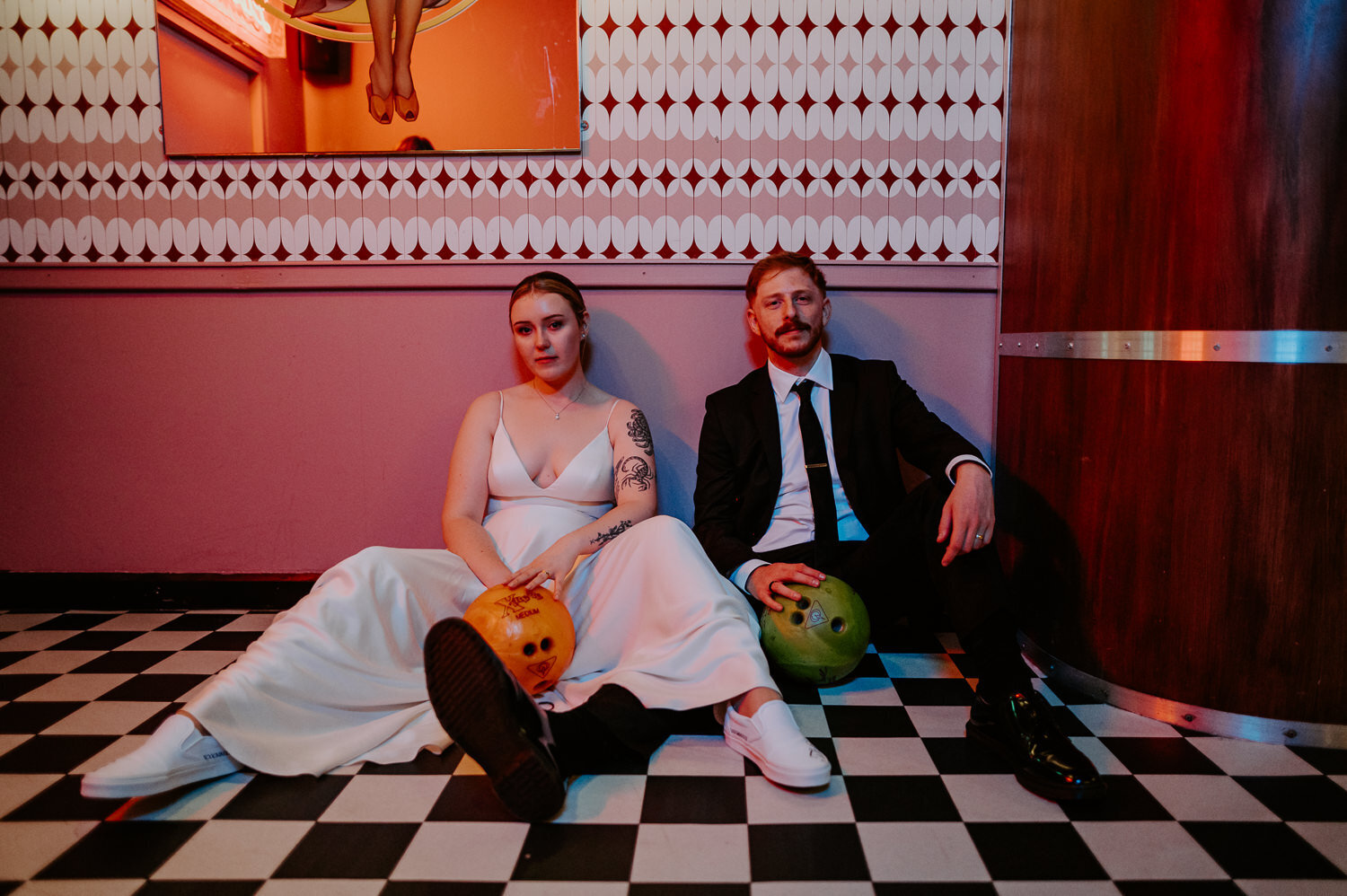 Cool wedding couple sat on the floor in a bowling alley in London