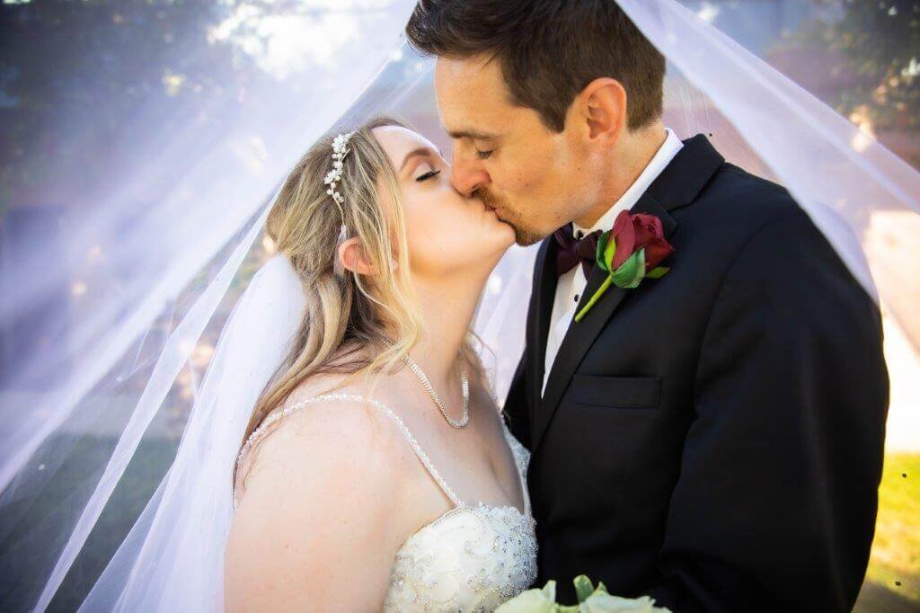 Wedding photography in Sacramento. Wedding couple kiss underneath the bride's veil.