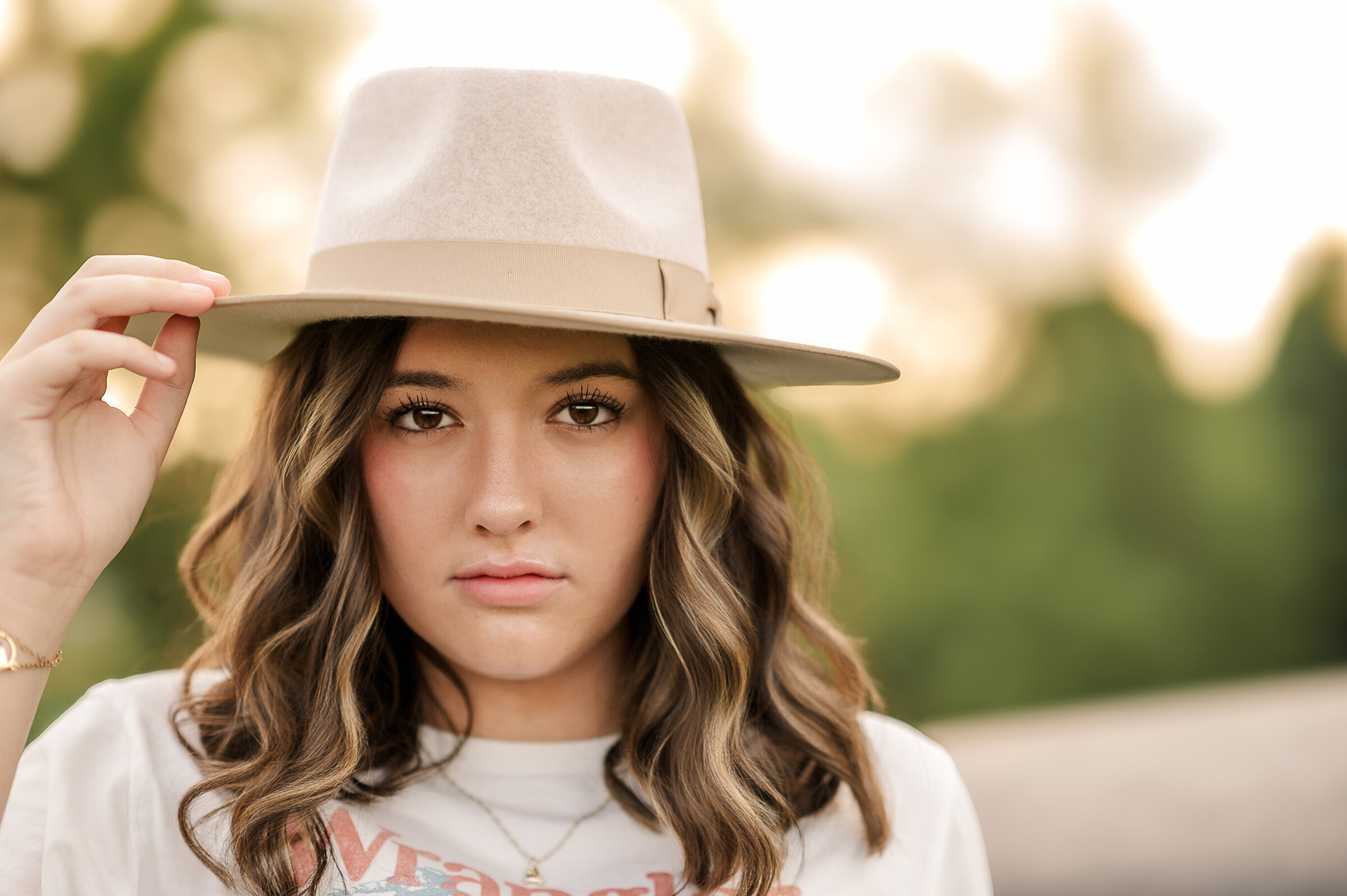 Close-up of a senior girl wearing a tan hat with golden hour light in the background lancaster pa