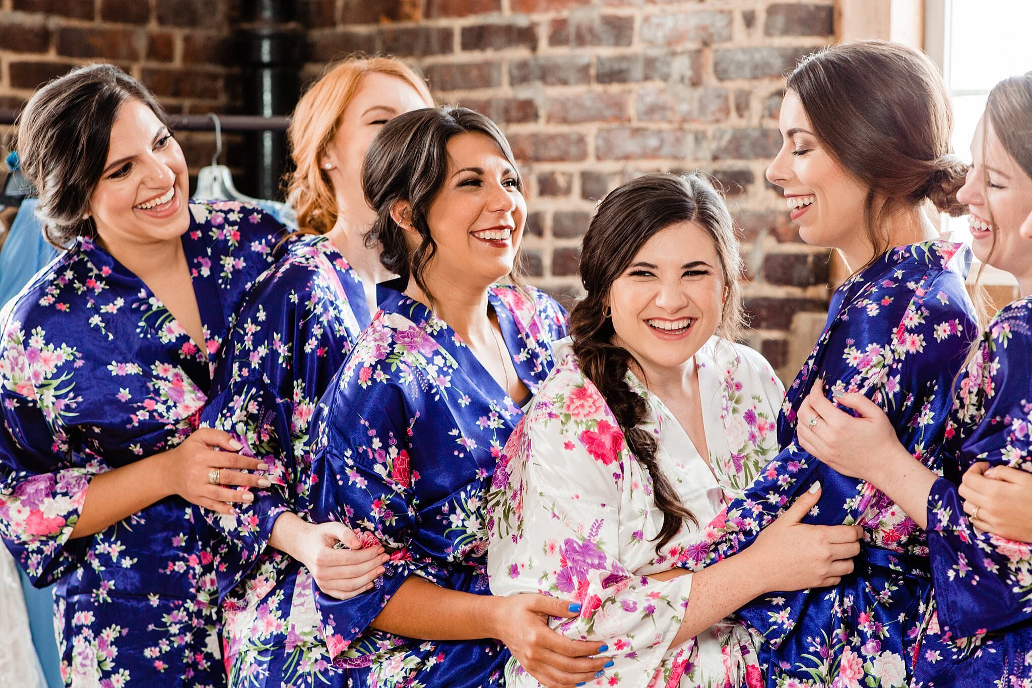 Bride with her girlfriends wearing robes and laughing together in the bridal suite at Cannery ONE