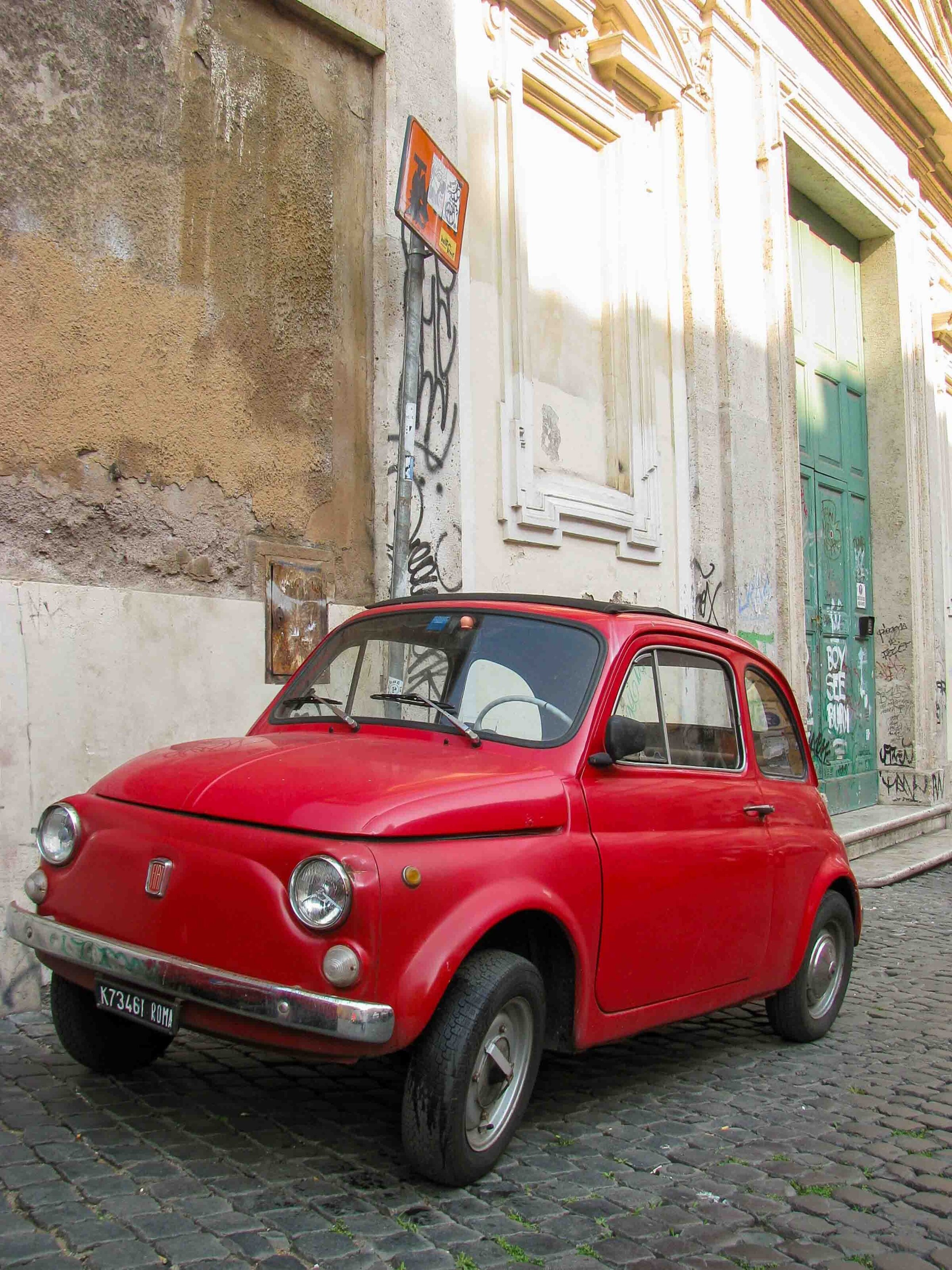 A red vintage Fiat car parked on a cobblestone backstreet of Rome, Italy ©Stephanie Dosch | theViatrix Luxury Travel