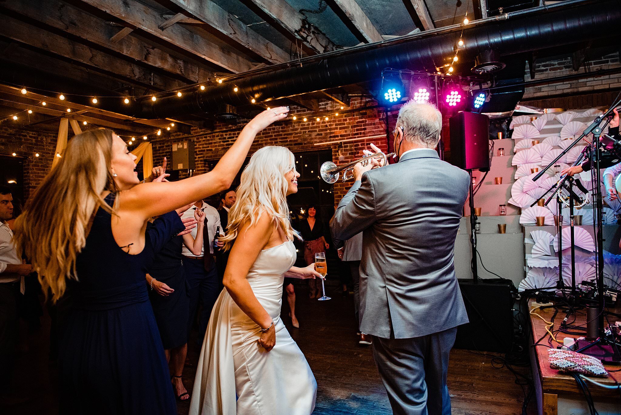 Father of the groom playing the trumpet during his sons reception, his daughter in law is dancing alongside him