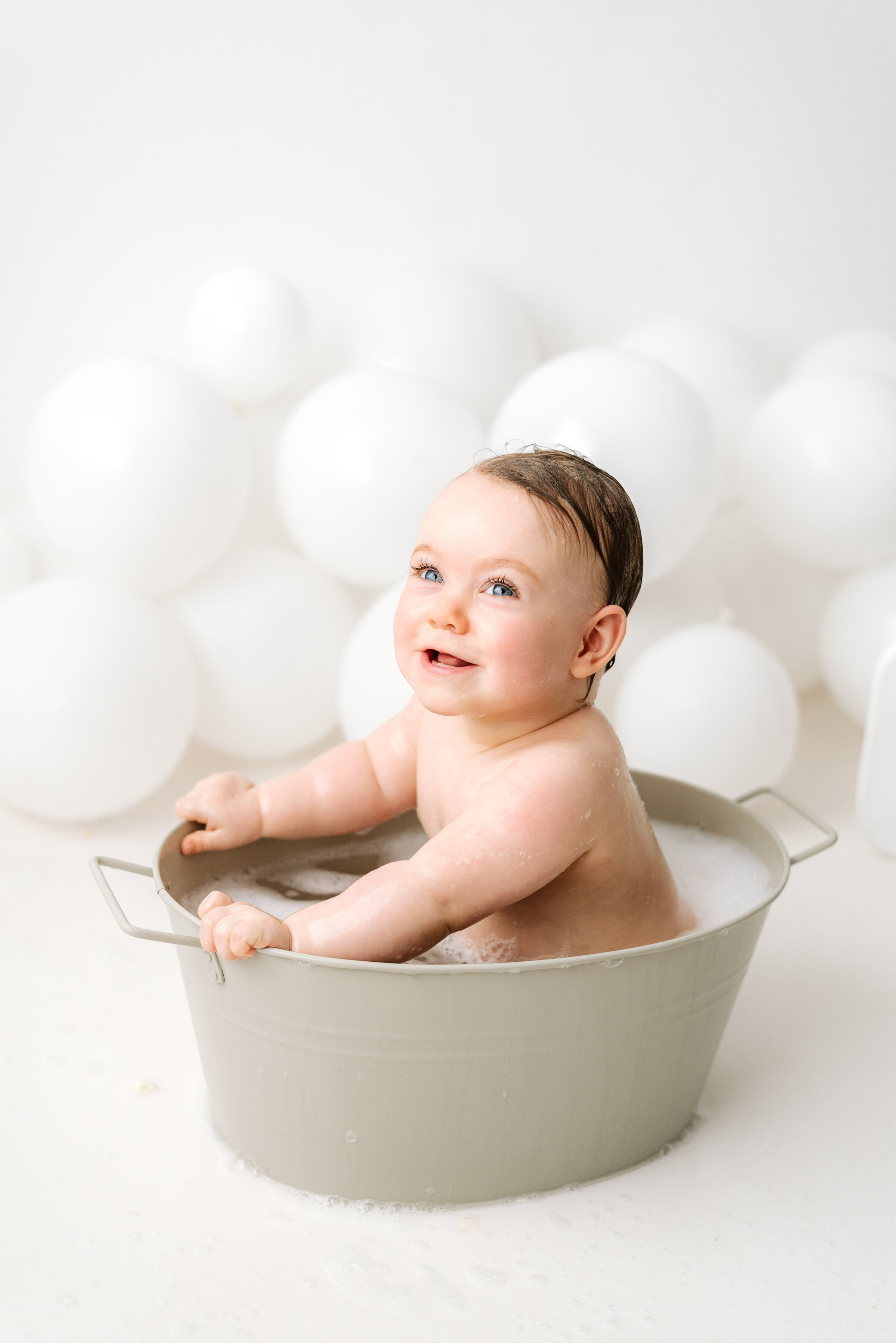 1 year old girl in bubble bath smiling at billingshurst cake smash photoshoot
