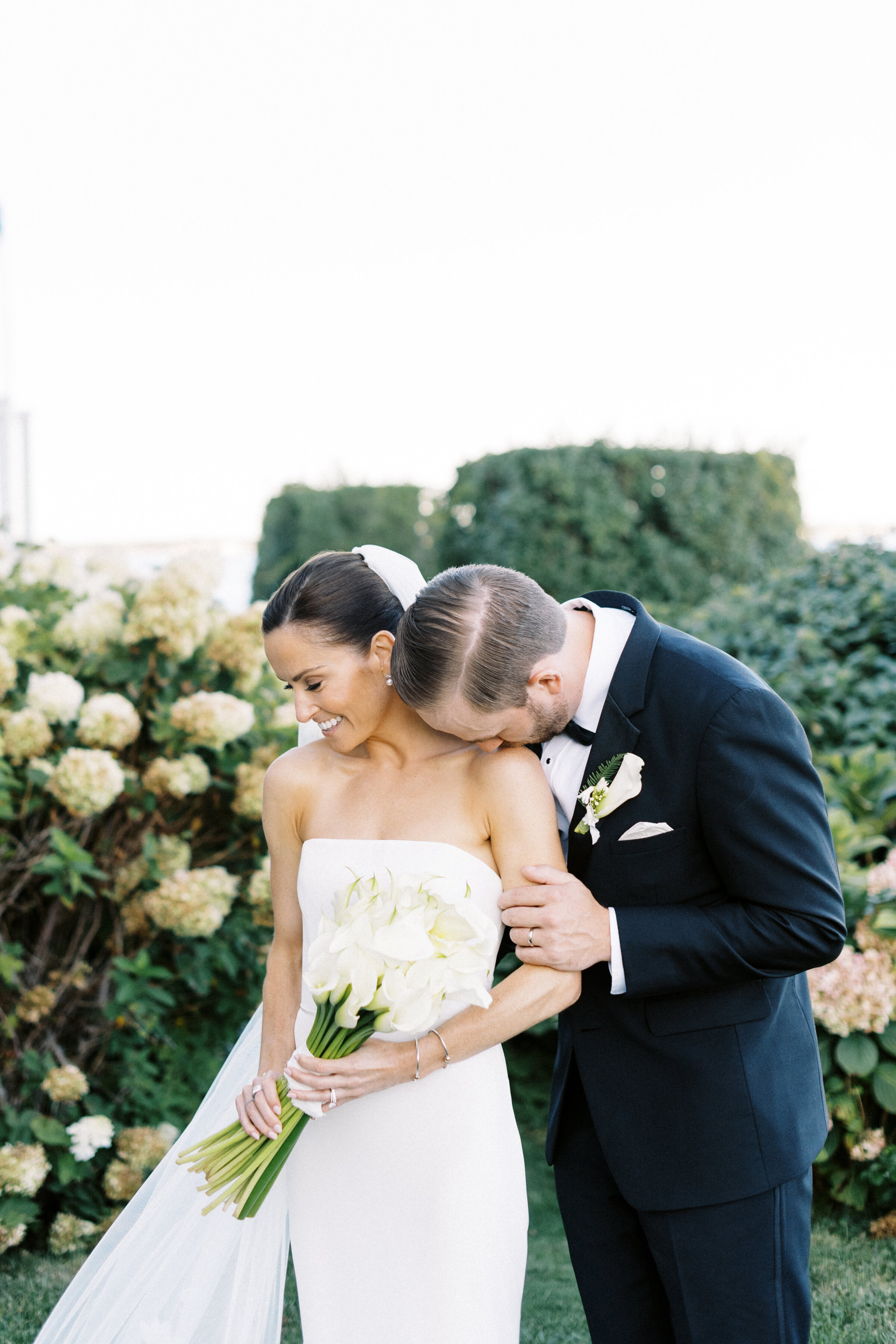 Newlyweds snuggle for portraits among the hydrangea bushes at fall Wianno Club wedding captured by Cape Cod wedding Photographer Lynne Reznick