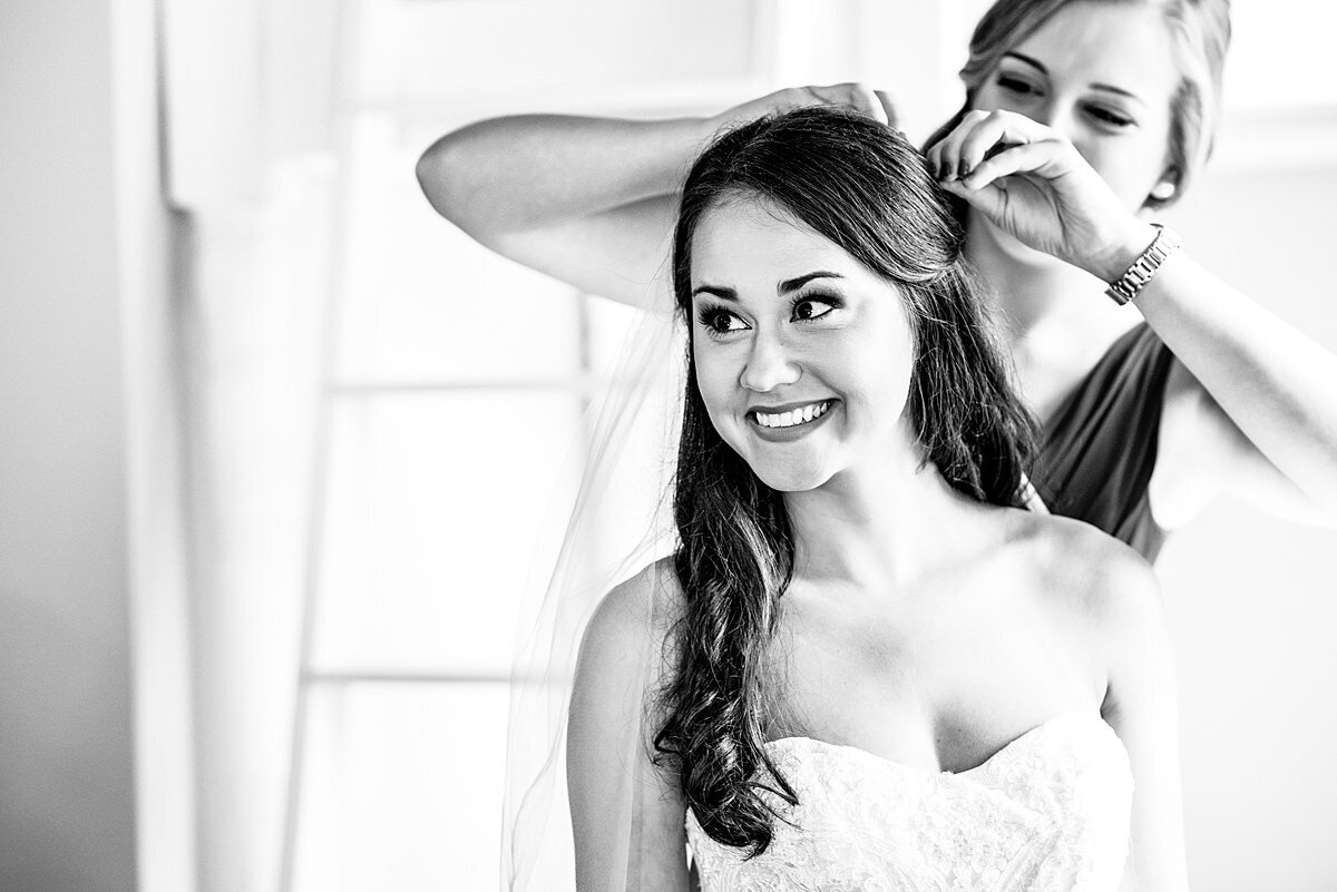 Bride smiling at her mom as her maid of honor is putting in her veil
