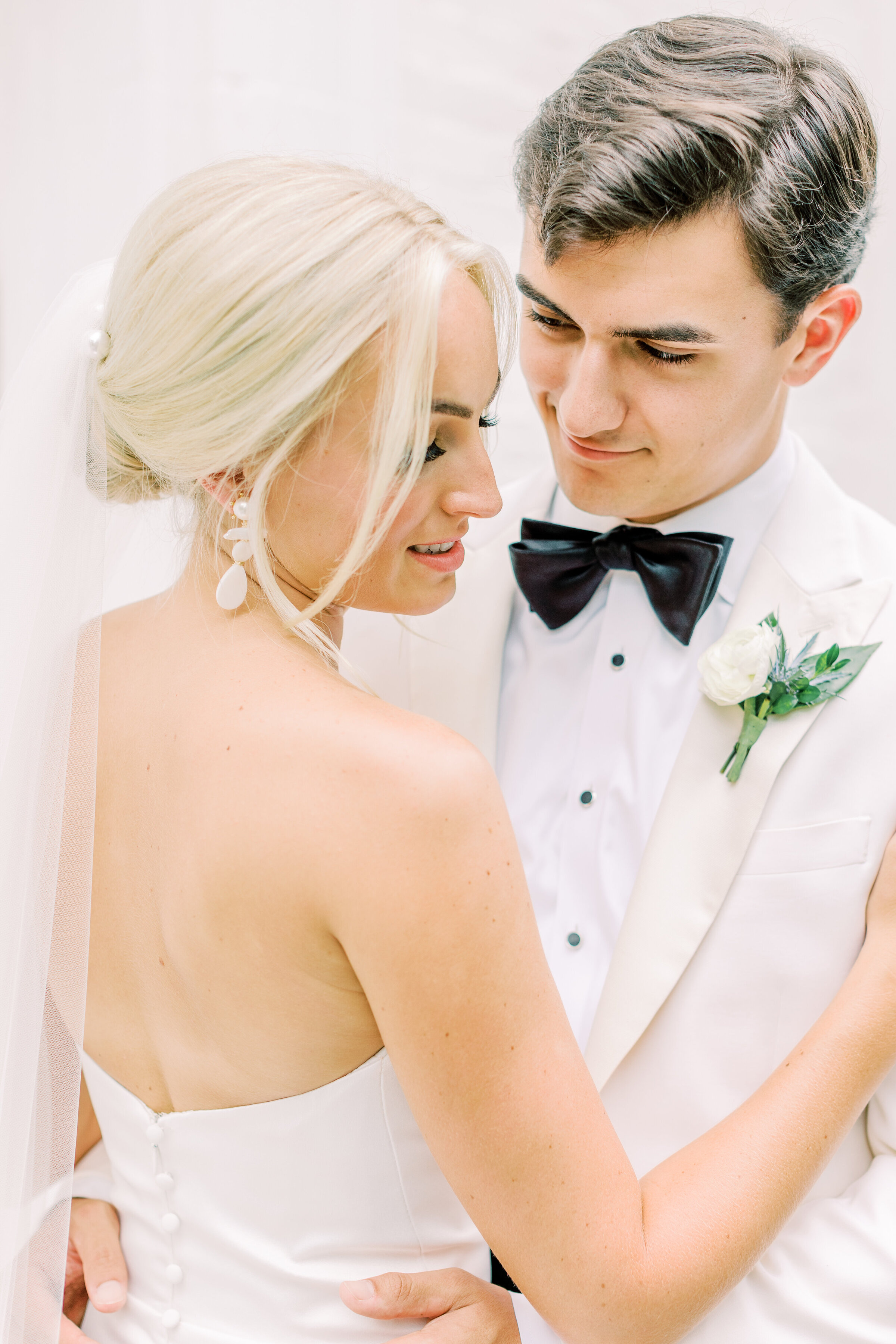 Bride and groom wearing white embracing