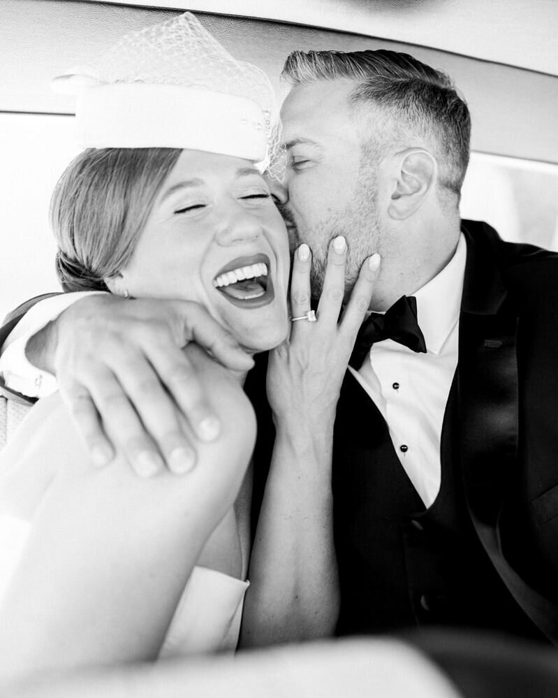 This joyful image captures the bride and groom laughing together in the back of a luxury wedding car after their first look. Photographed in Calgary, Alberta, the couple's happiness shines through, reflecting the excitement and love they share on their special day.
