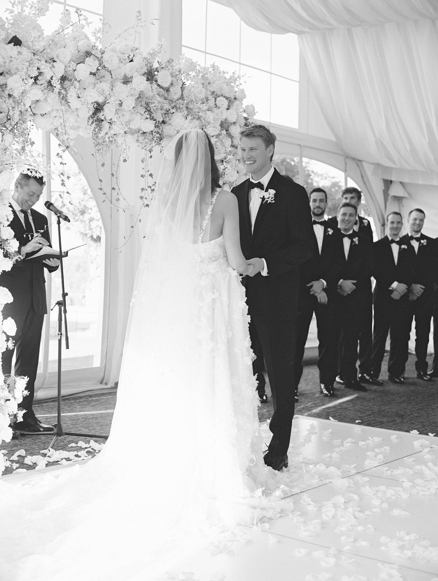 bw photo of groom smiling at bride during wedding ceremony