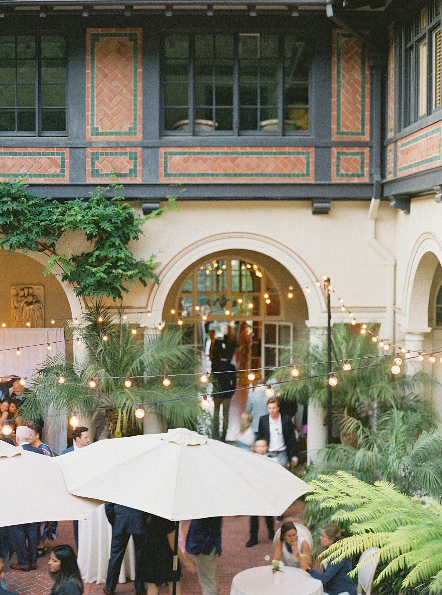 saratoga ca spanish villa wedding venue at cocktail hour with bistro lights and umbrellas