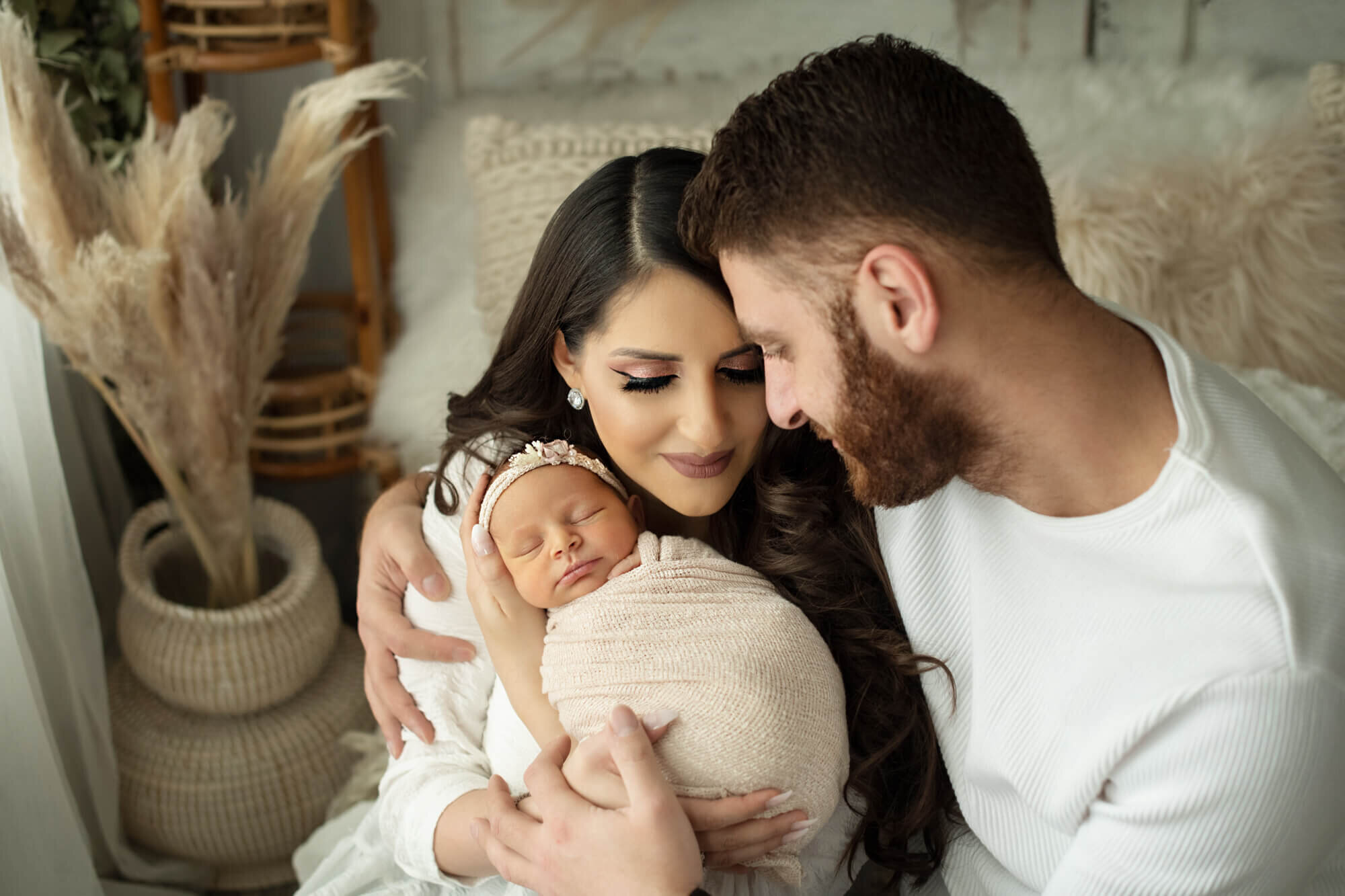 Parents holding newborn baby in boho studio setting