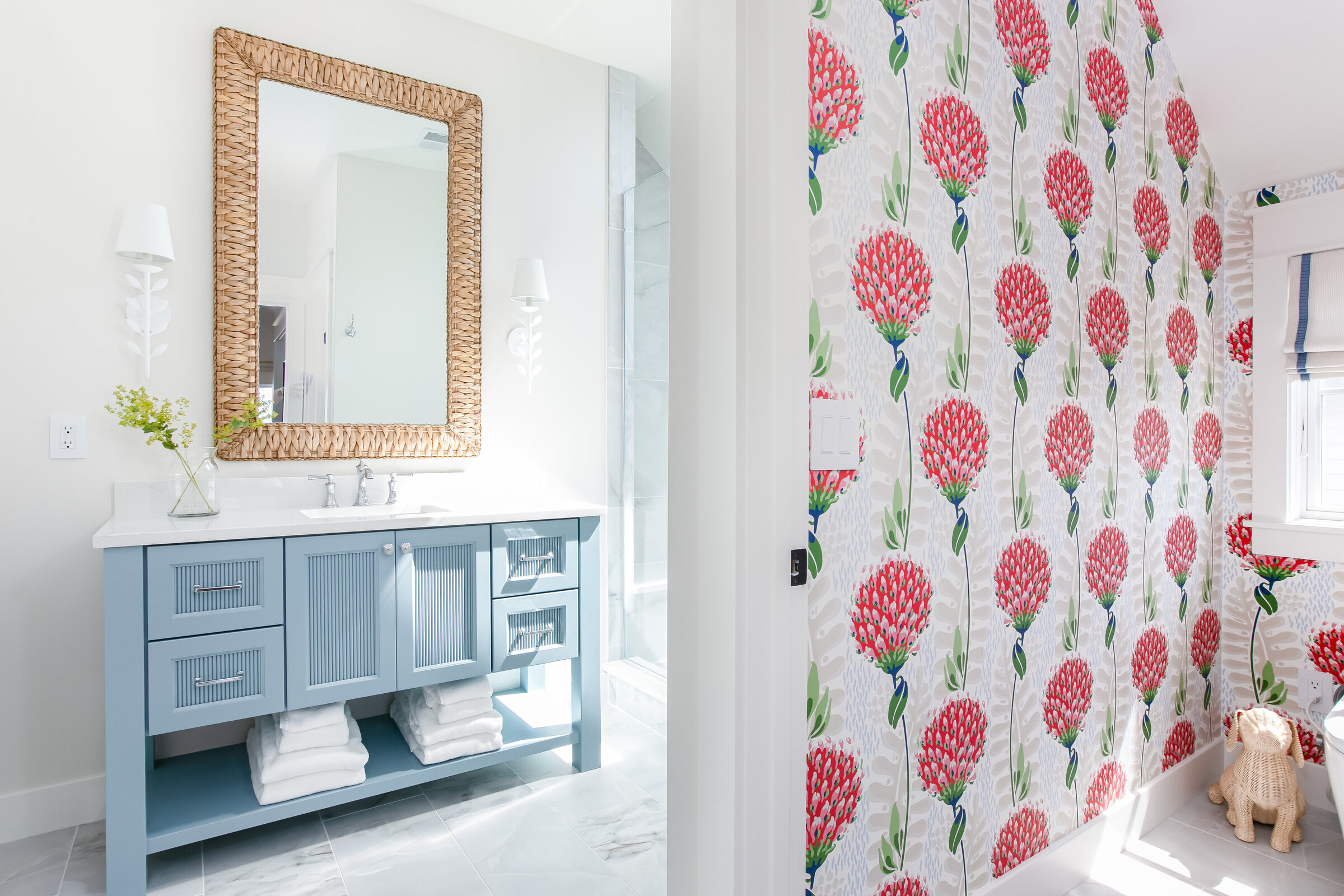 A vibrant bedroom featuring playful, bright wallpaper, leading into a bathroom with a striking blue vanity. The design blends bold colors and cheerful patterns, creating a lively and inviting space.