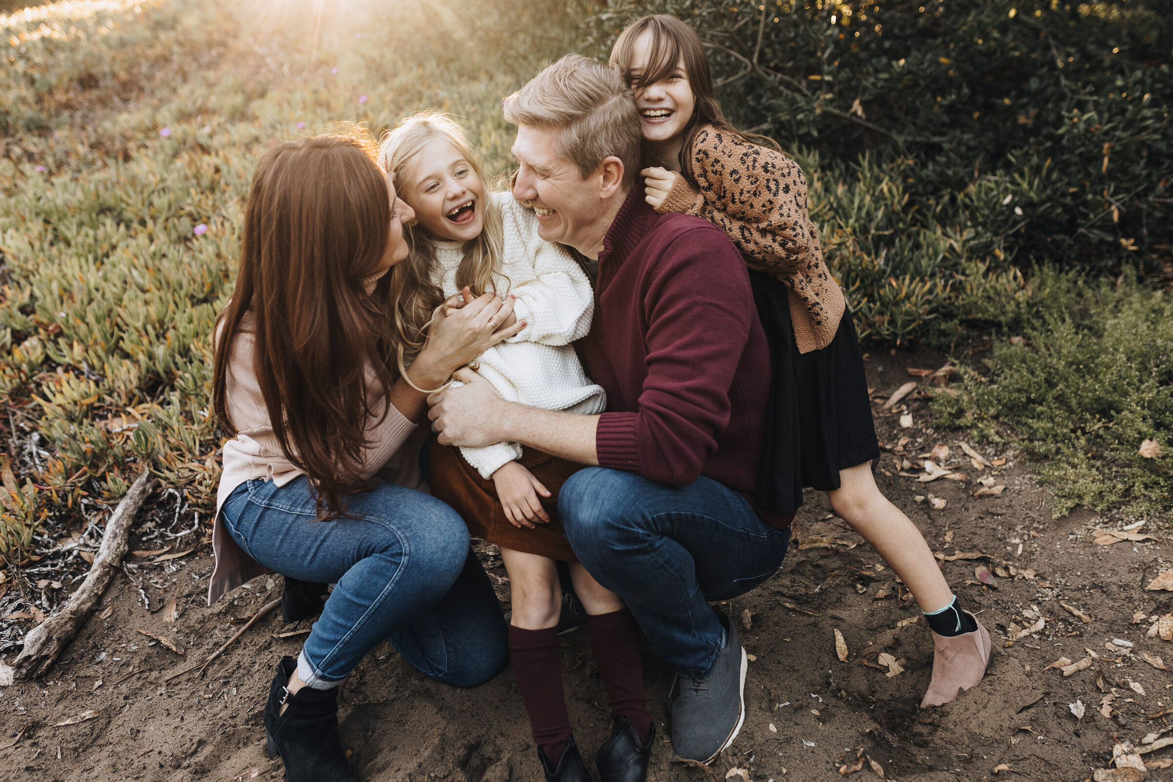Family laughs and falls over each other while the sun shines on them