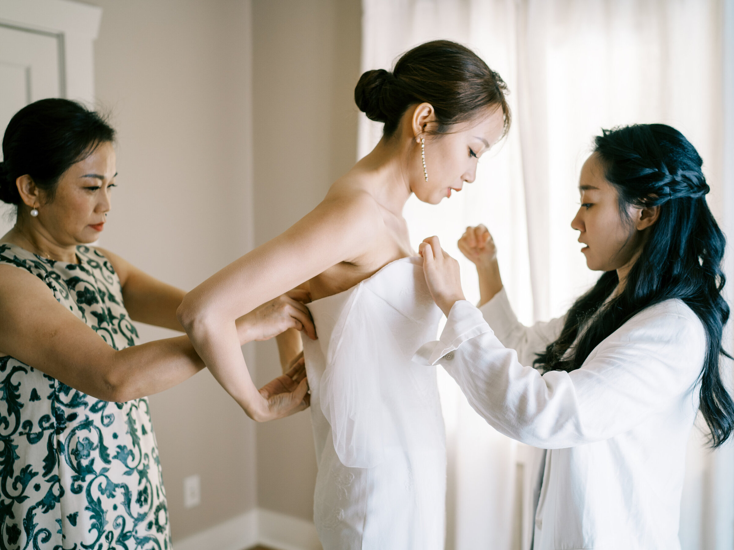 brides mother and bridesmaid get her dressed