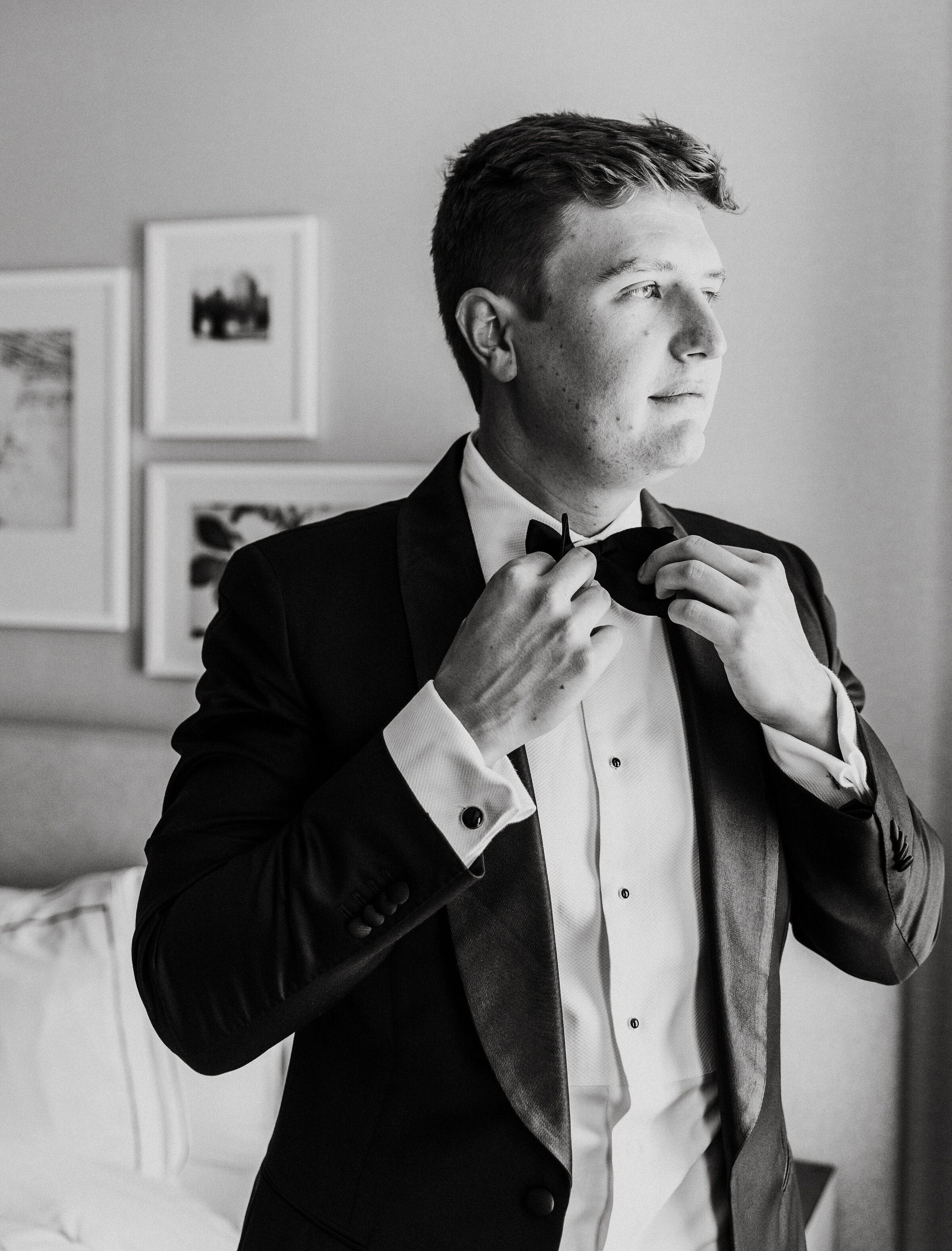 Groom adjusts bow tie before wedding ceremony at SRV Boston in Boston, Massachusetts