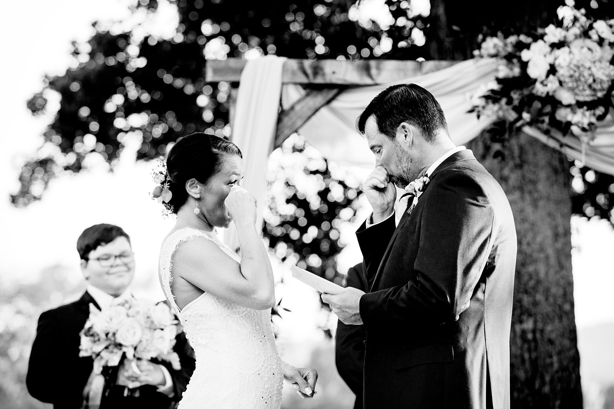 Black and white photo of couple emotionally crying during their vow exchange