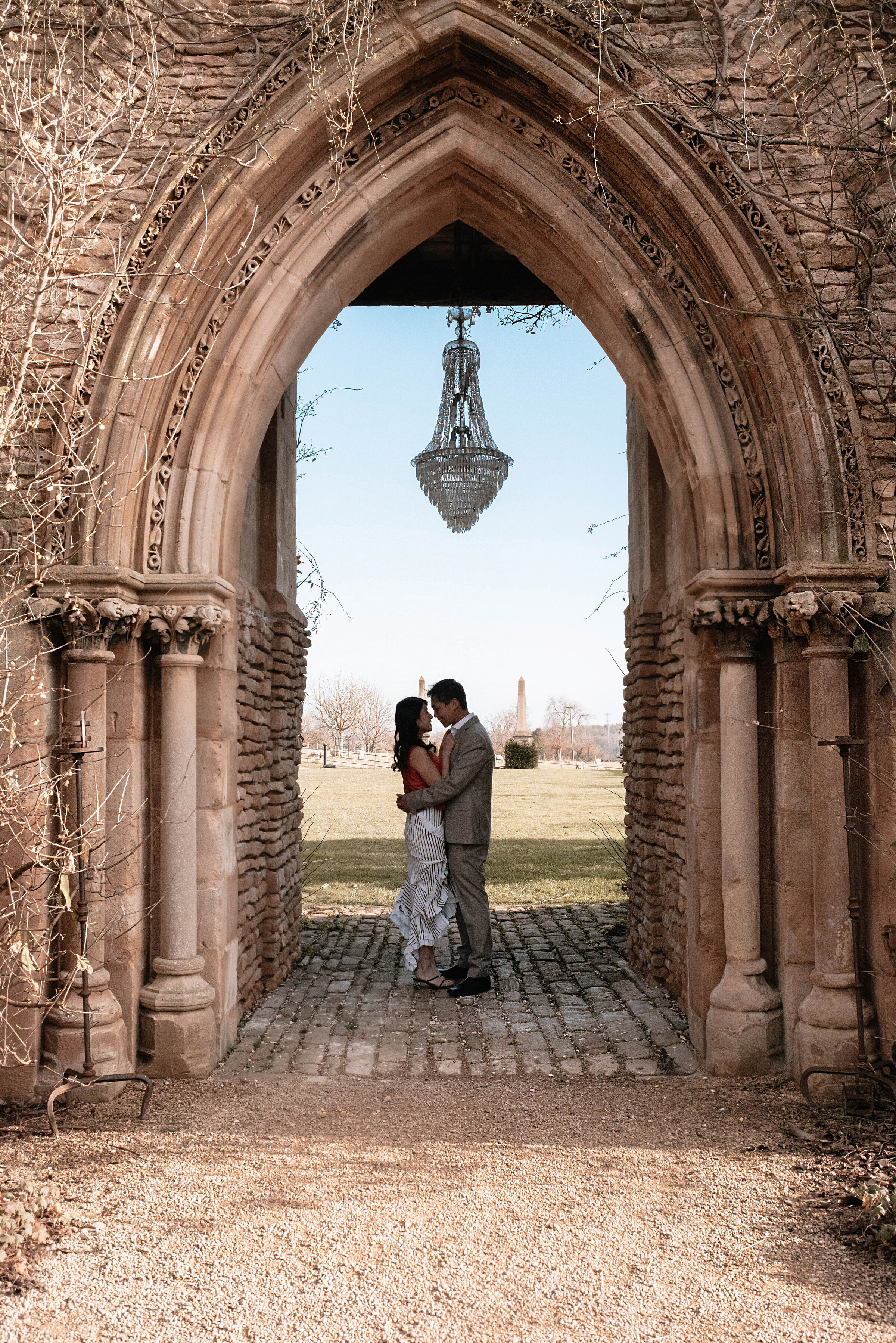 Man and woman embracing standing beneath the famous crystal chandelier hanging in the archway at Euridge Manor