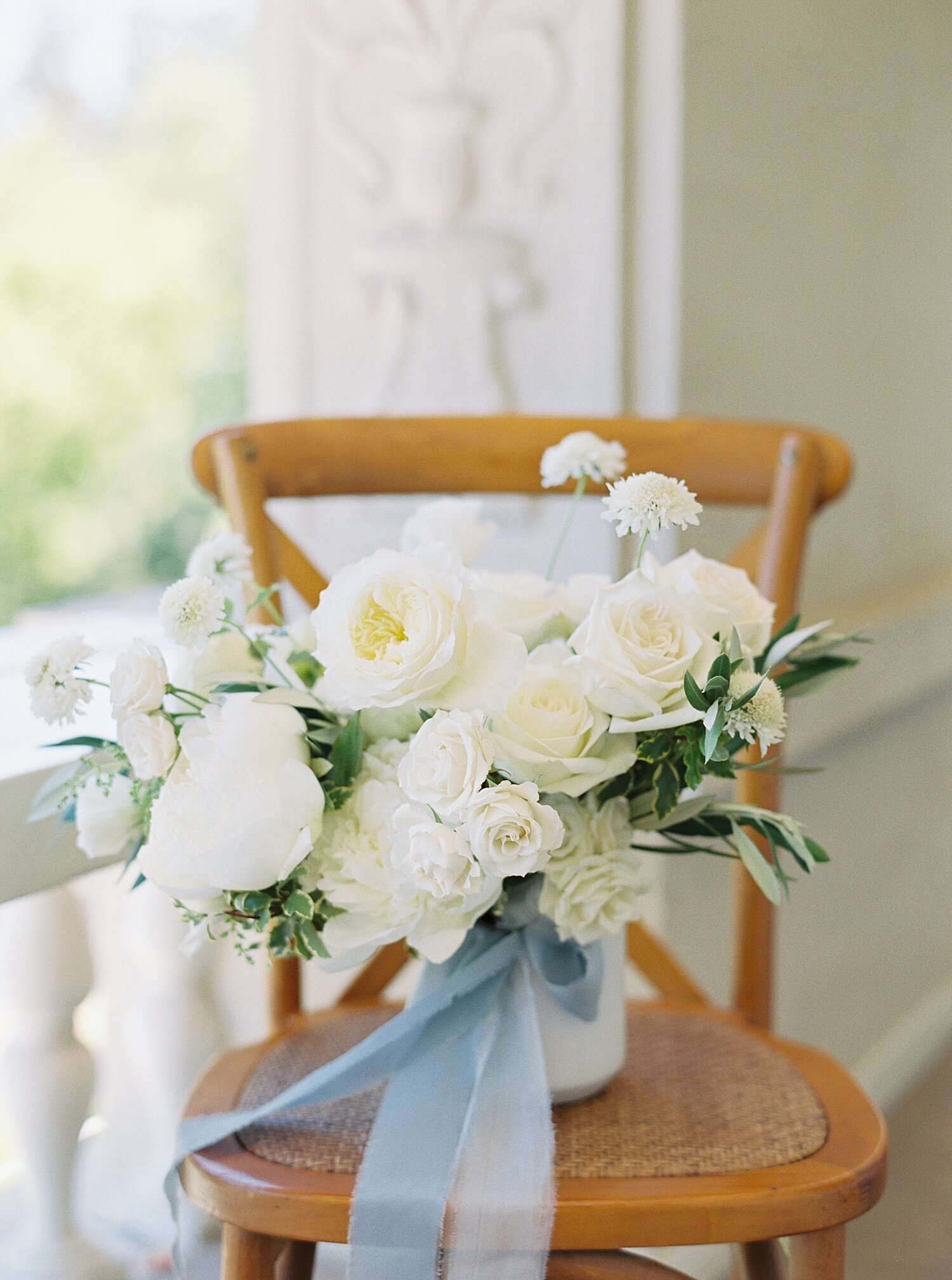 white and green bridal bouquet on brown wooden chair
