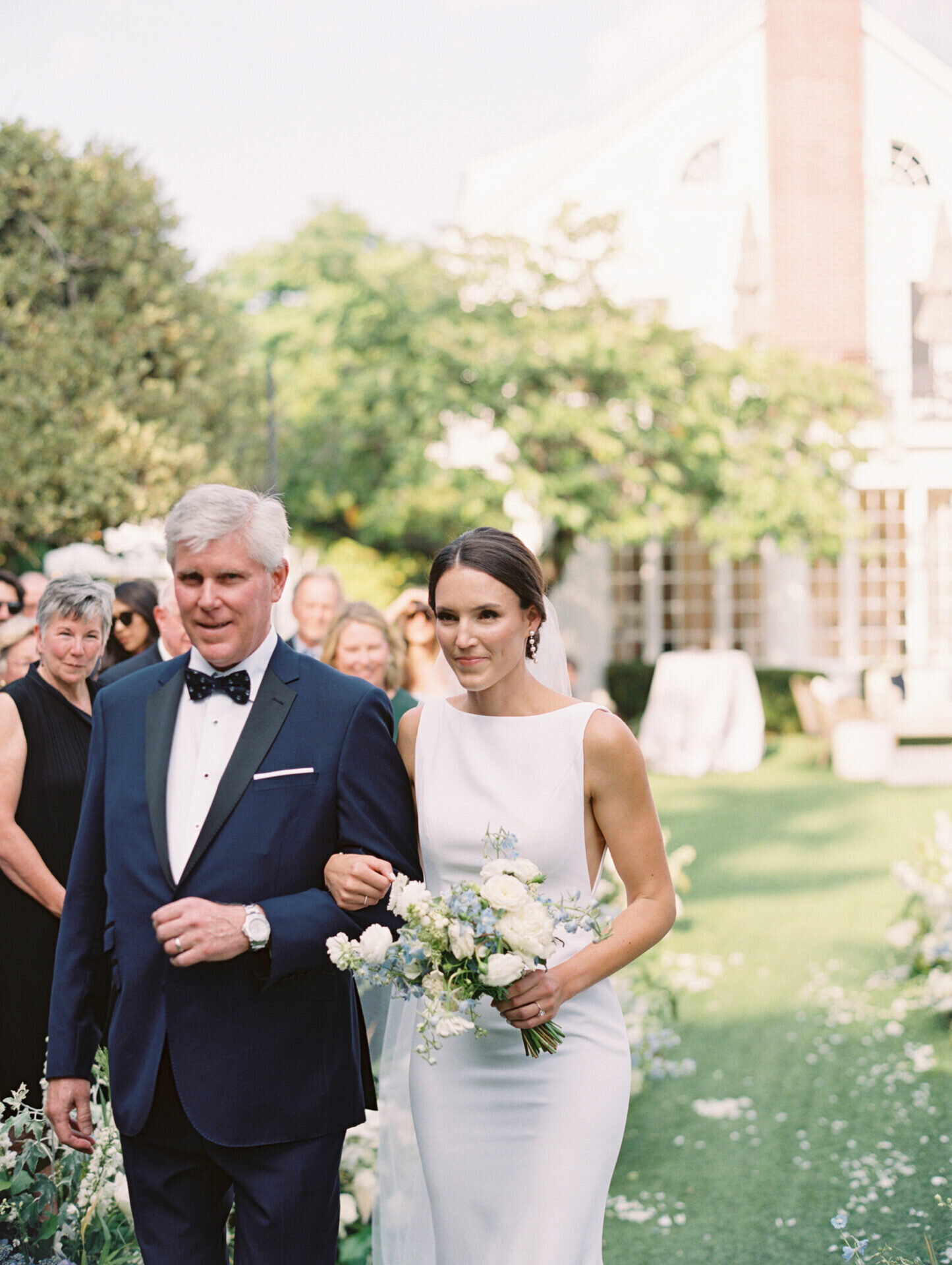 father walking his daughter the bride down the aisle with white green florals