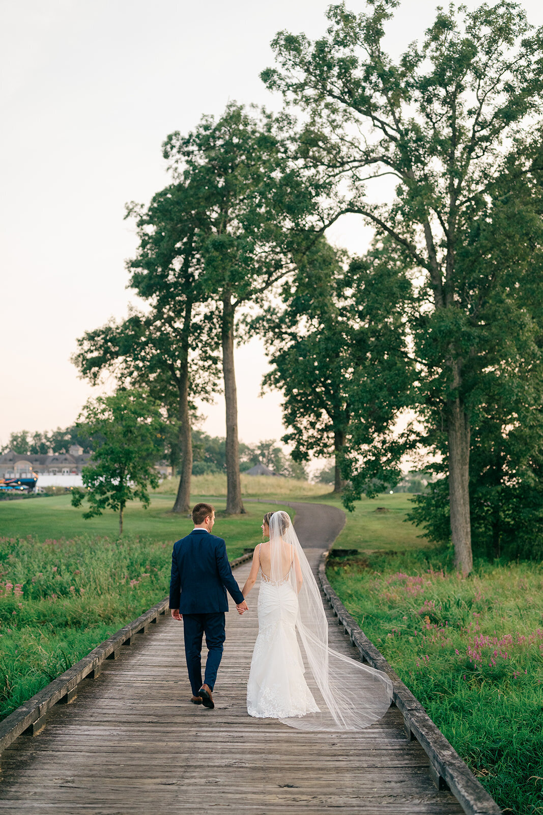 sunset at saratoga national golf course with the bride and groom walking hand in hand on their wedding day
