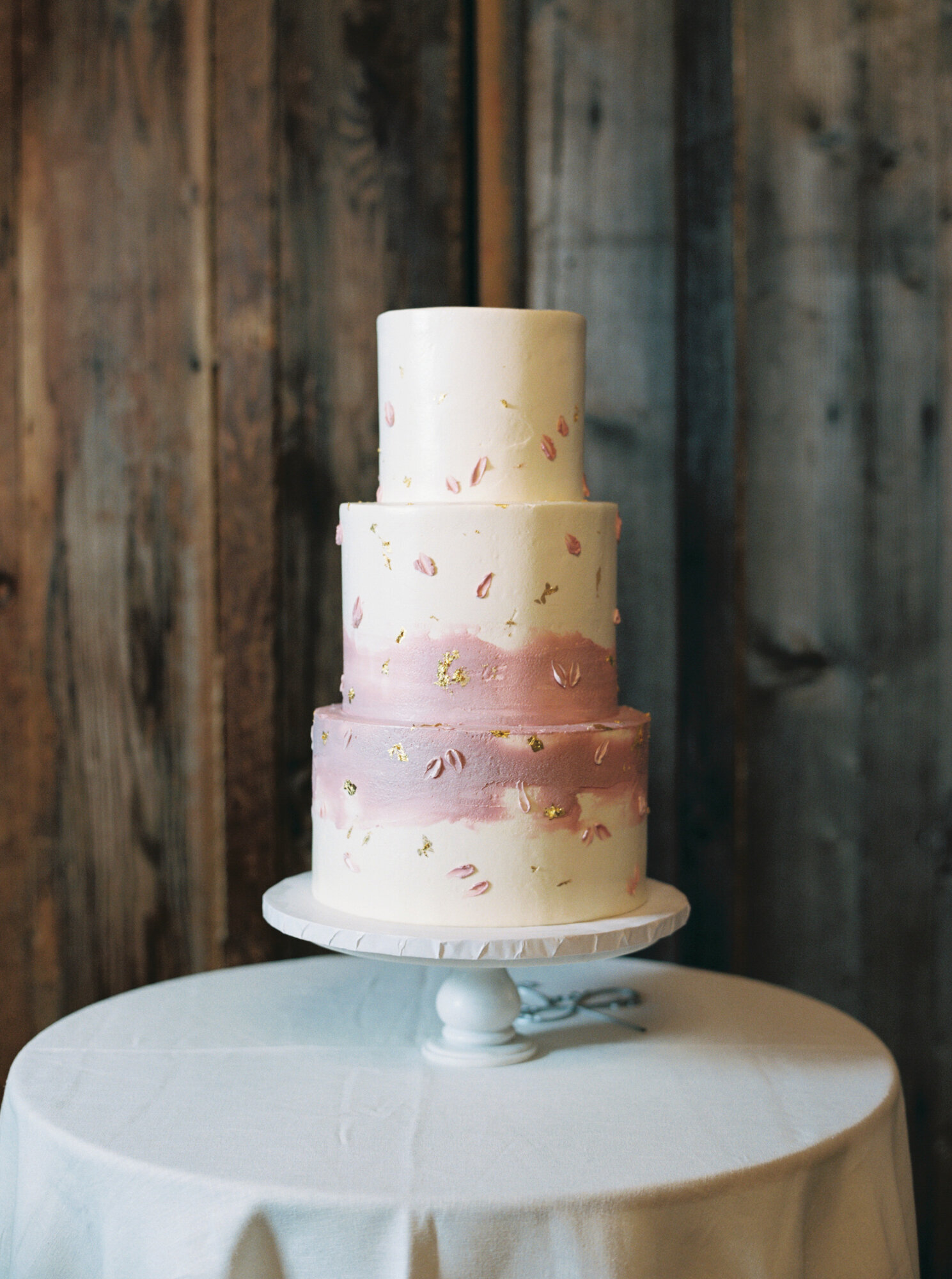 white and pink with small gold flecks three tiered wedding cake