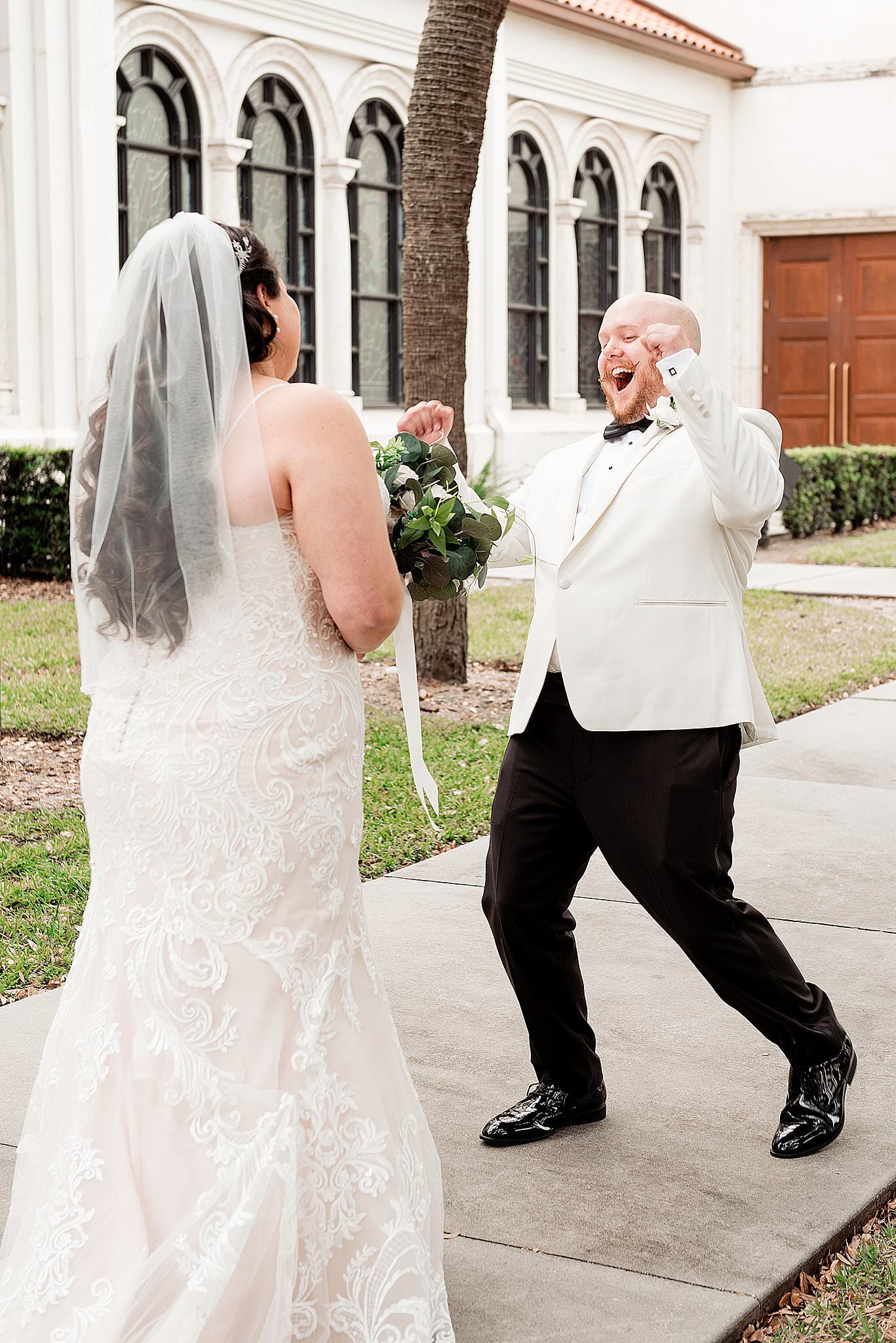 Groom with handlebar mustache  and ivory jacket expressing his excitement at seeing his fiance for the first time on their wedding day