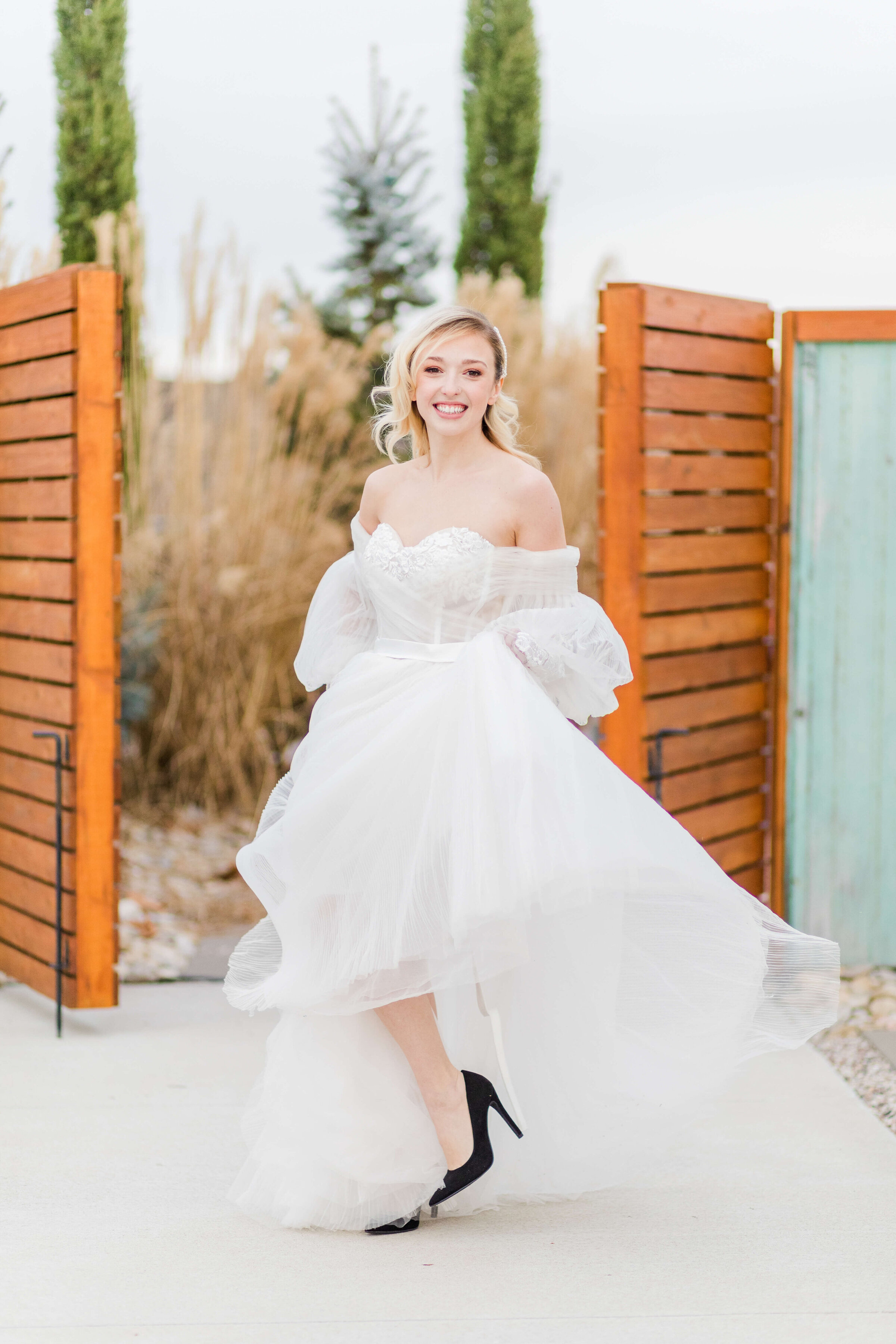 A bride in a white dress and black heels twirls around with excitement.