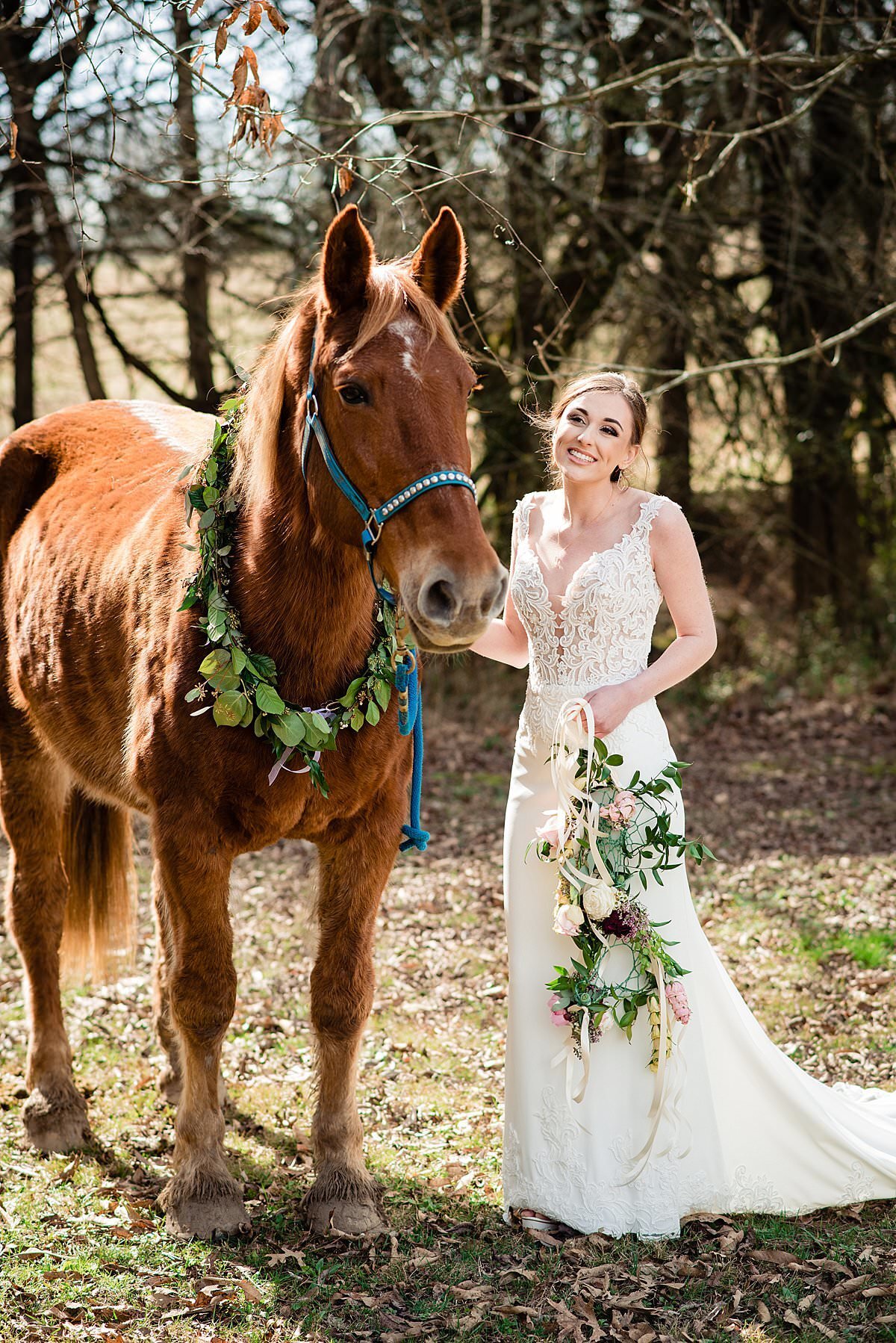 Bride holding a whimsical dream catcher with florals and standing beside her horse