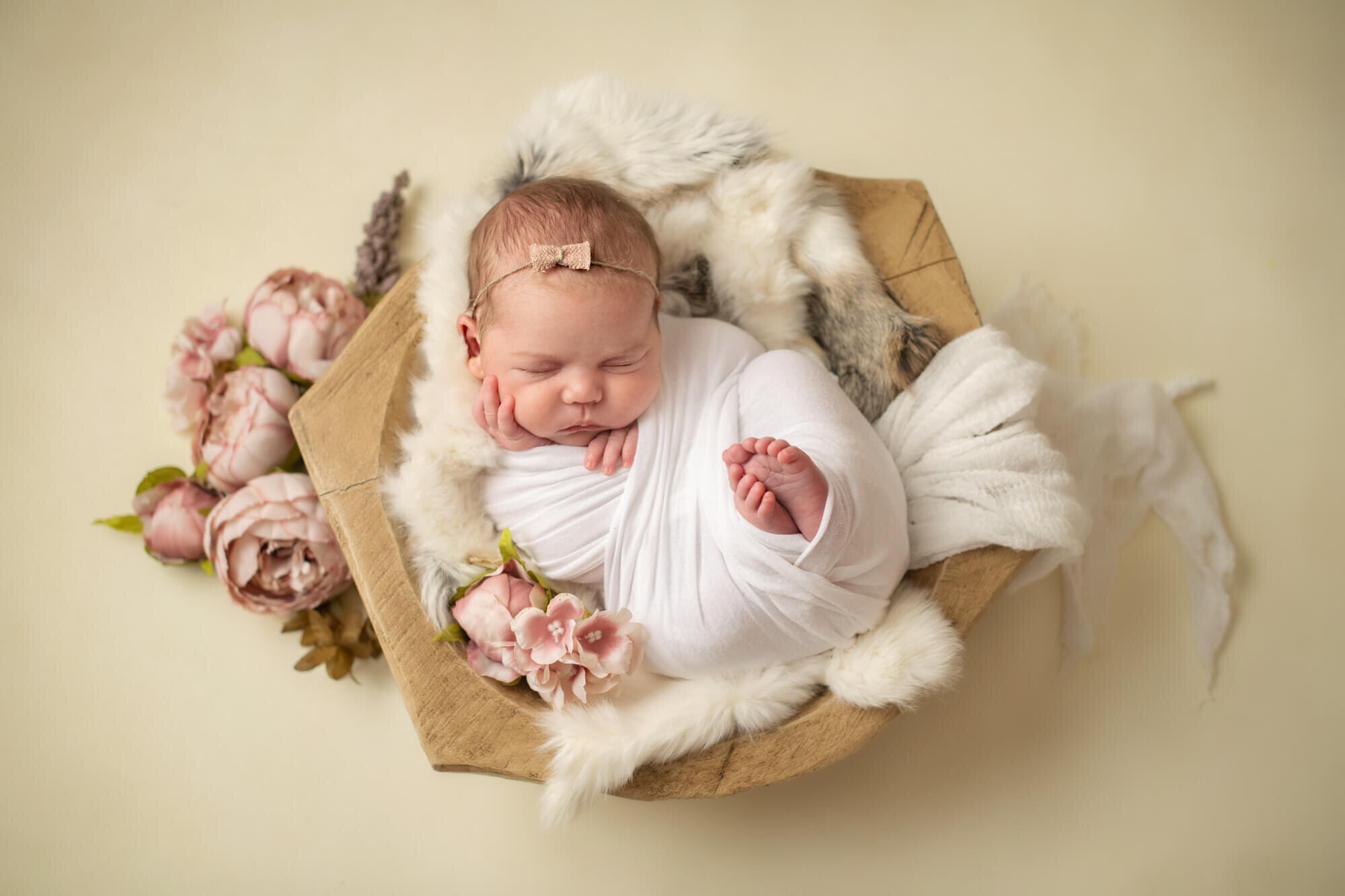 Sleeping baby girl in white wrap with florals and wooden bowl