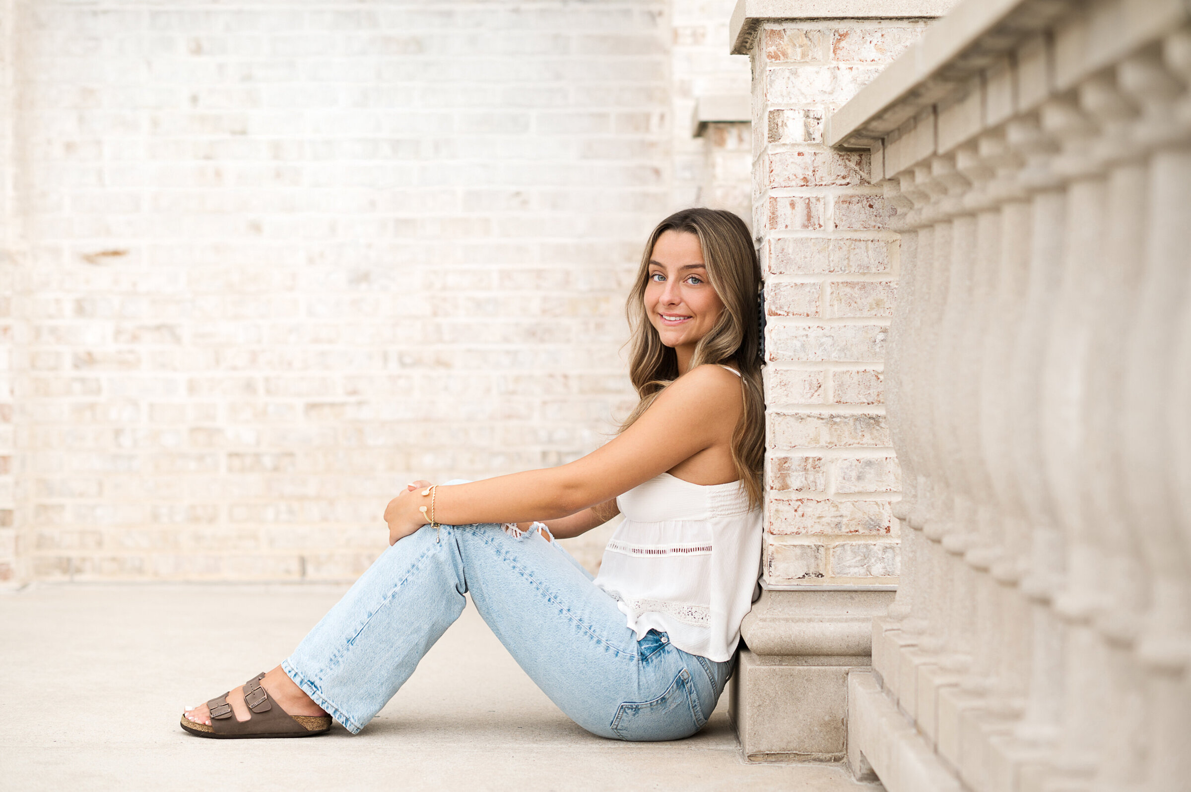 High school senior sitting against a white brick wall at Hershey Gardens near Harrisburg and Lancaster PA, photographed by York PA senior photographer Kara Michelle.