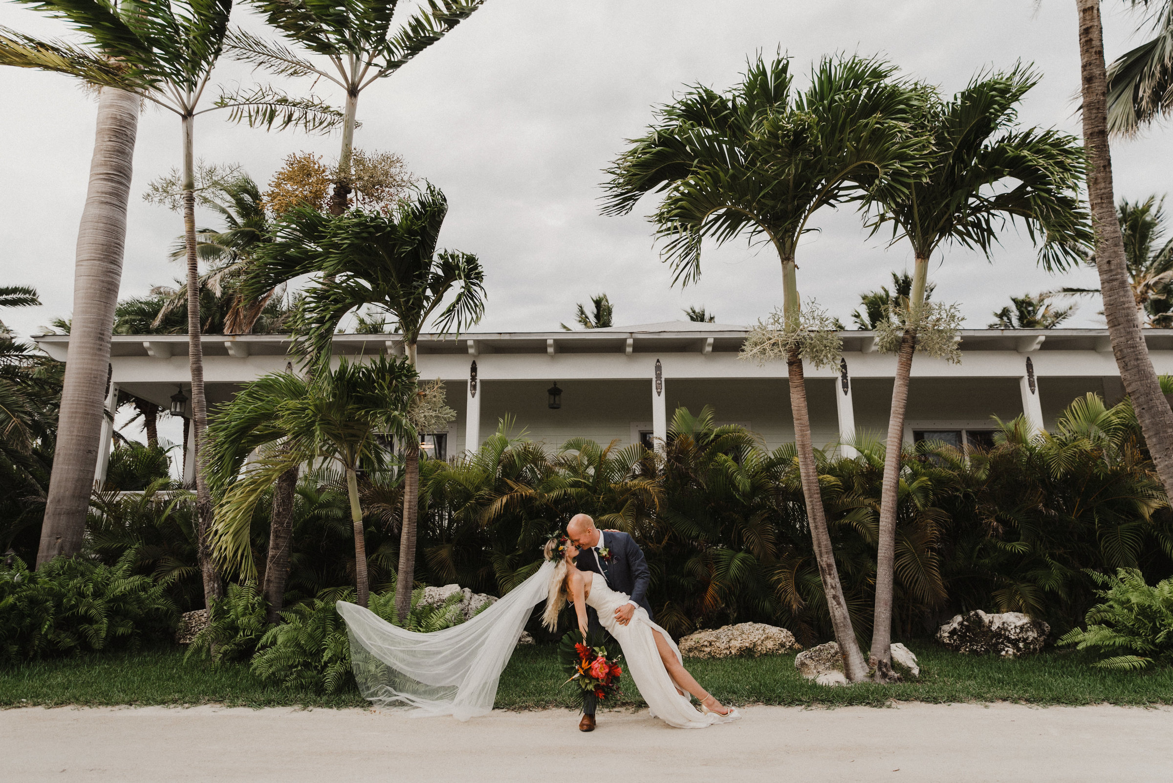 bride under the palm trees dip kiss