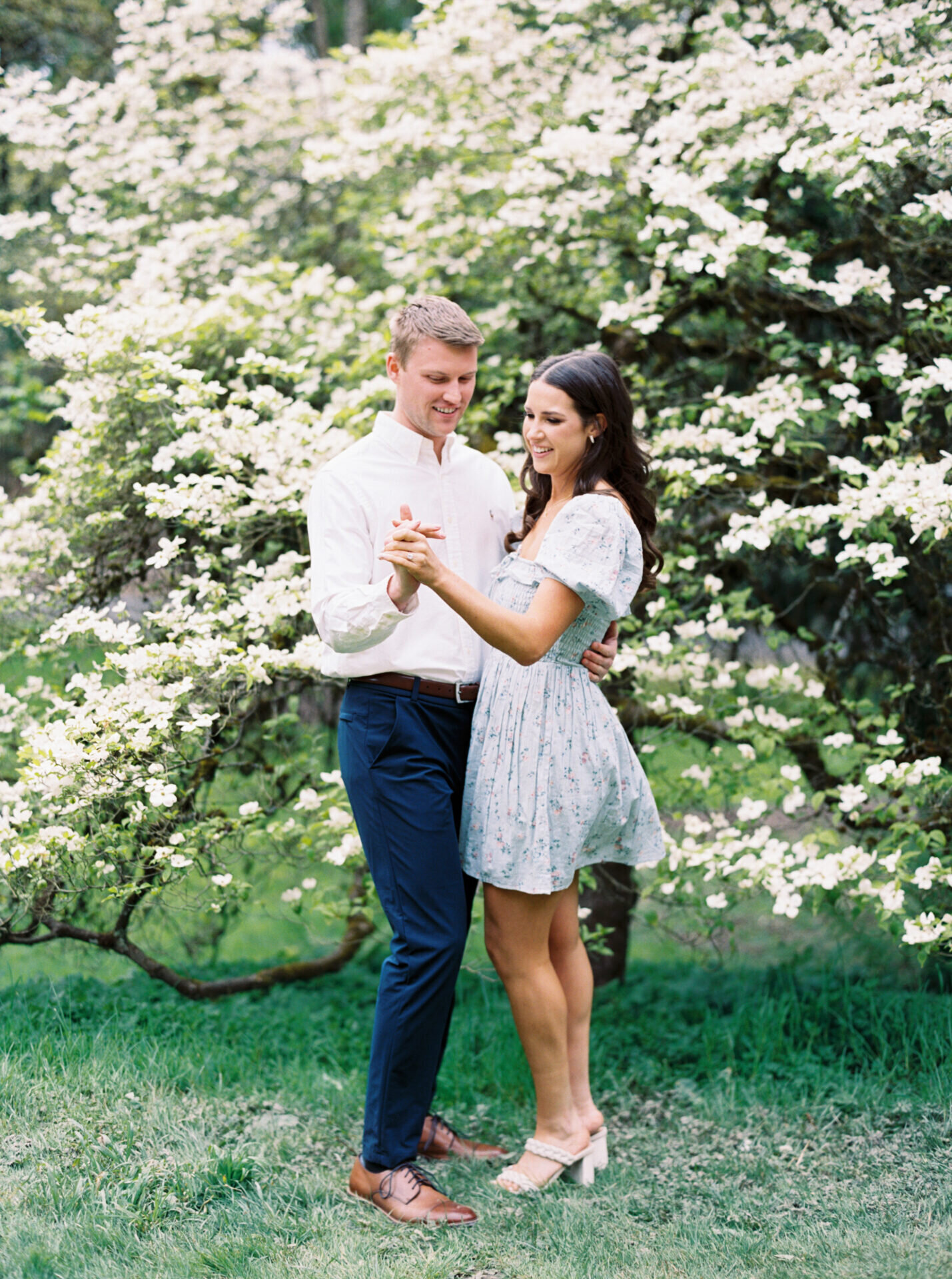 white spring blossom tree with couple dancing in front of it
