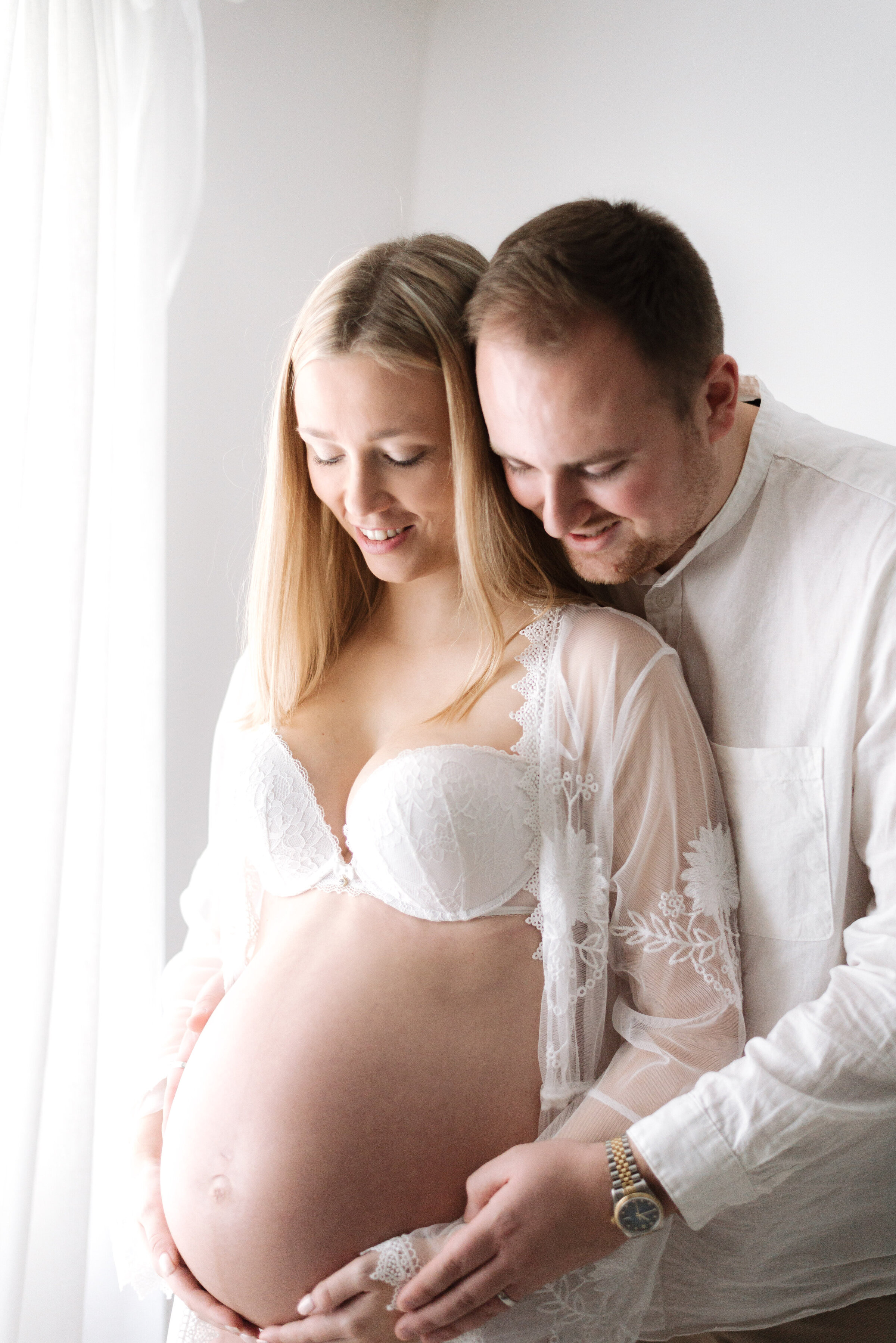 Pregnant mother with father hugging at maternity photoshoot in Billingshurst