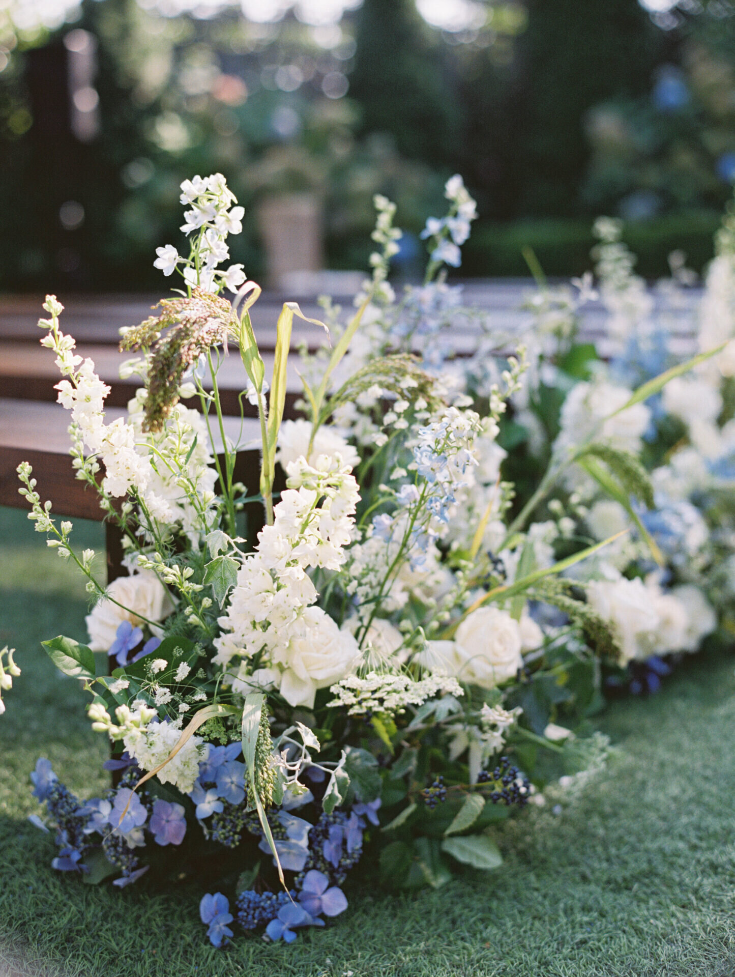 white and periwinkle florals lining ceremony on green grass