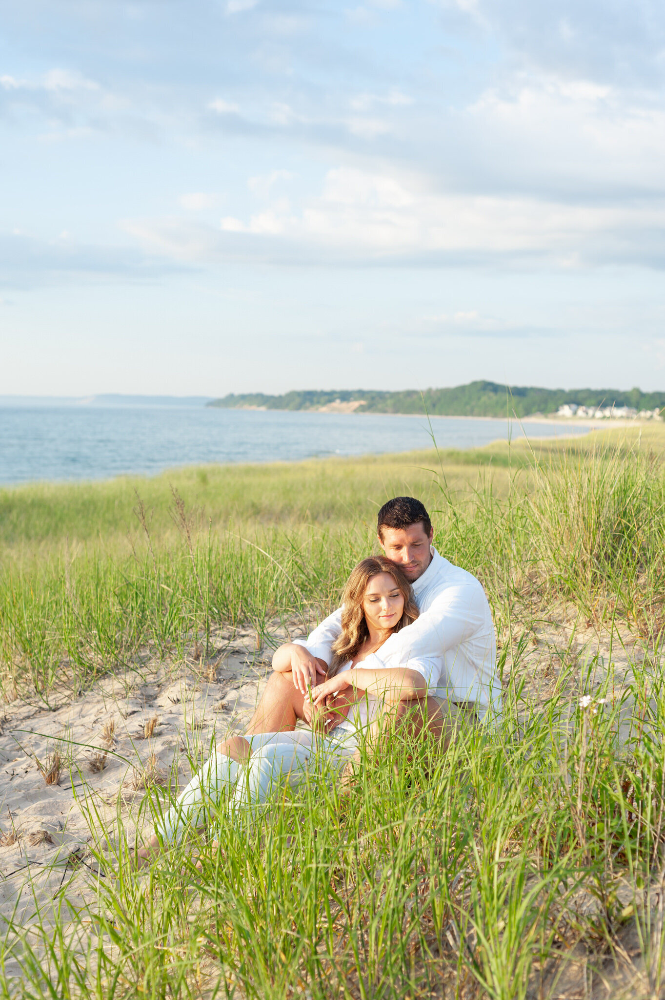 couple cuddled up in the sand and beach grass
