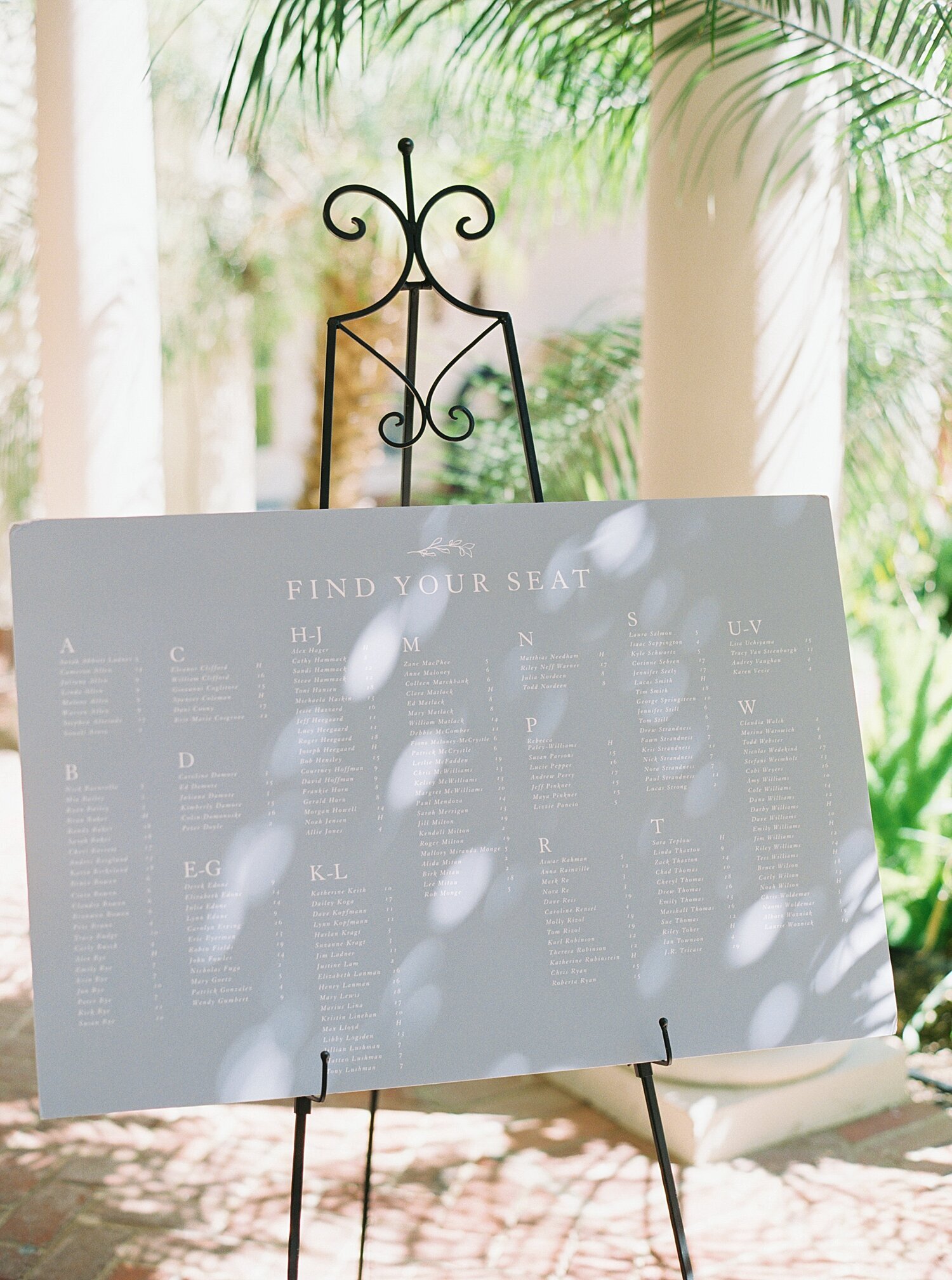 light blue and white wedding seating chart on easel
