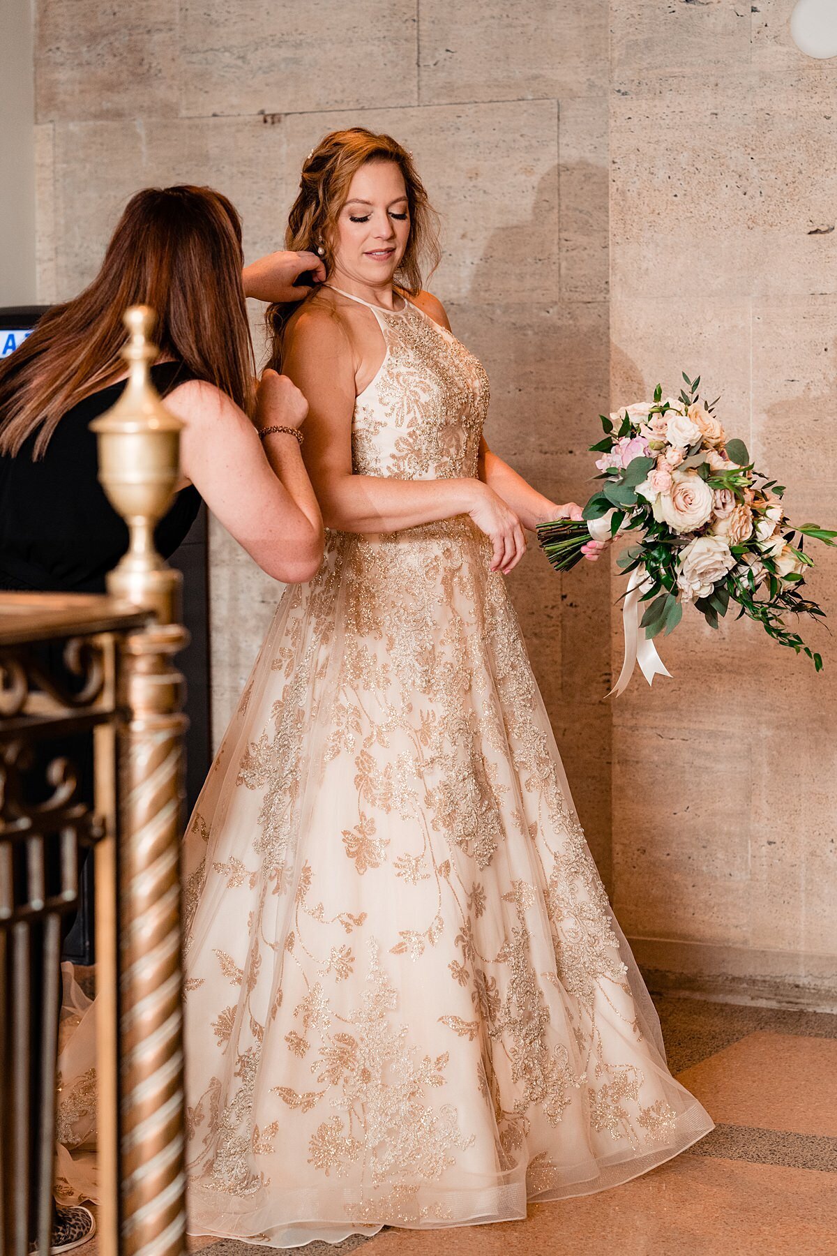 Photography asssitant helping bride with her dress before her first look