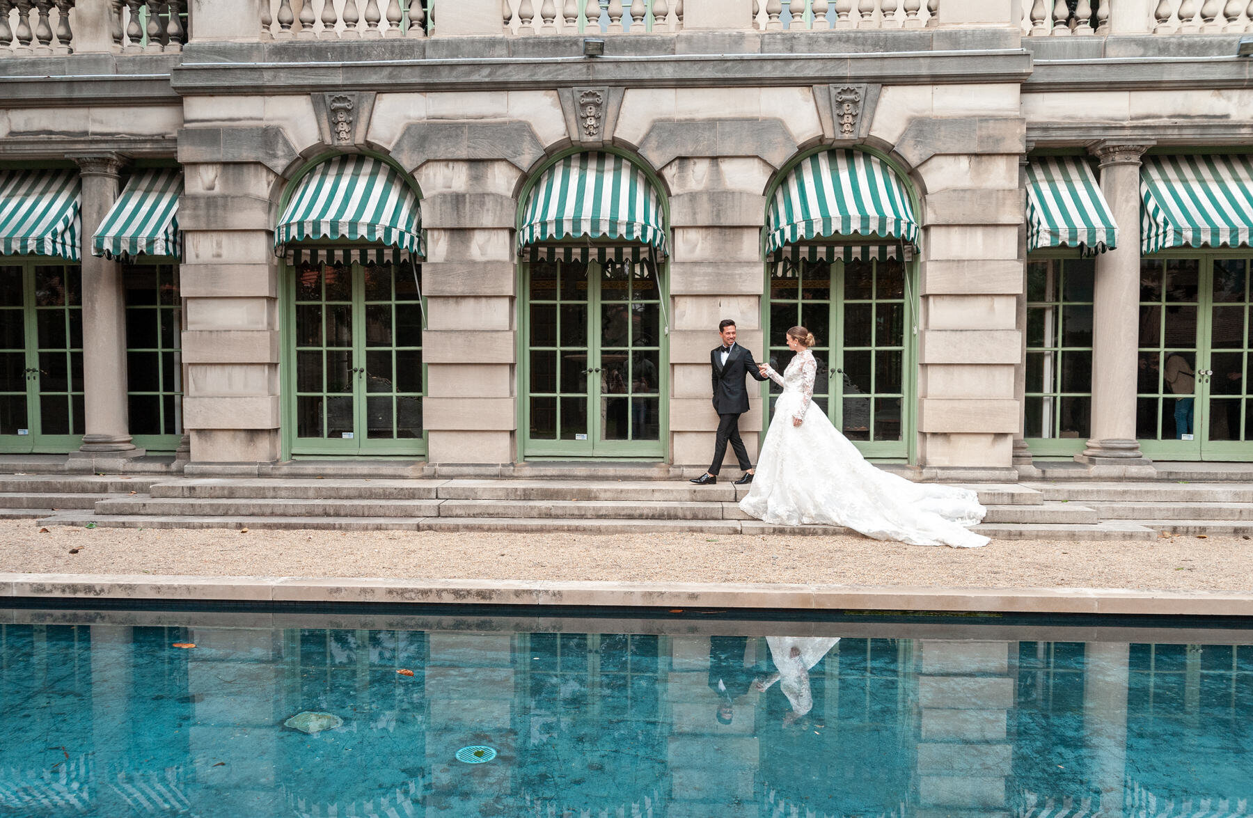 bride and groom walking across the Anderson House terrace in front of the reflecting pool