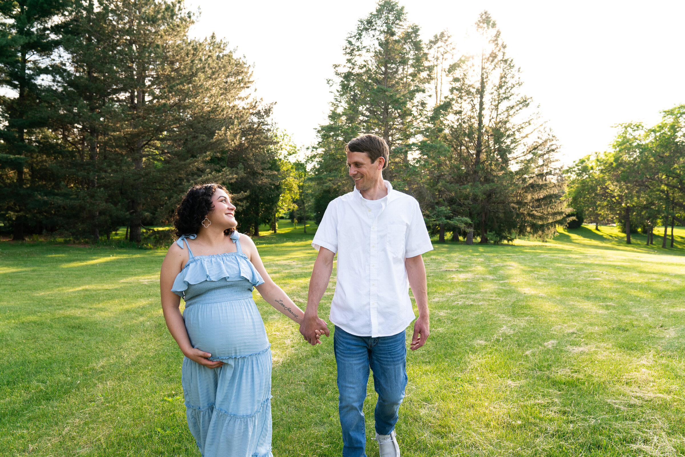 Couple walking toward the camera looking at each other during their maternity photo shoot at Arneson Acres Park in Edina, Minnesota