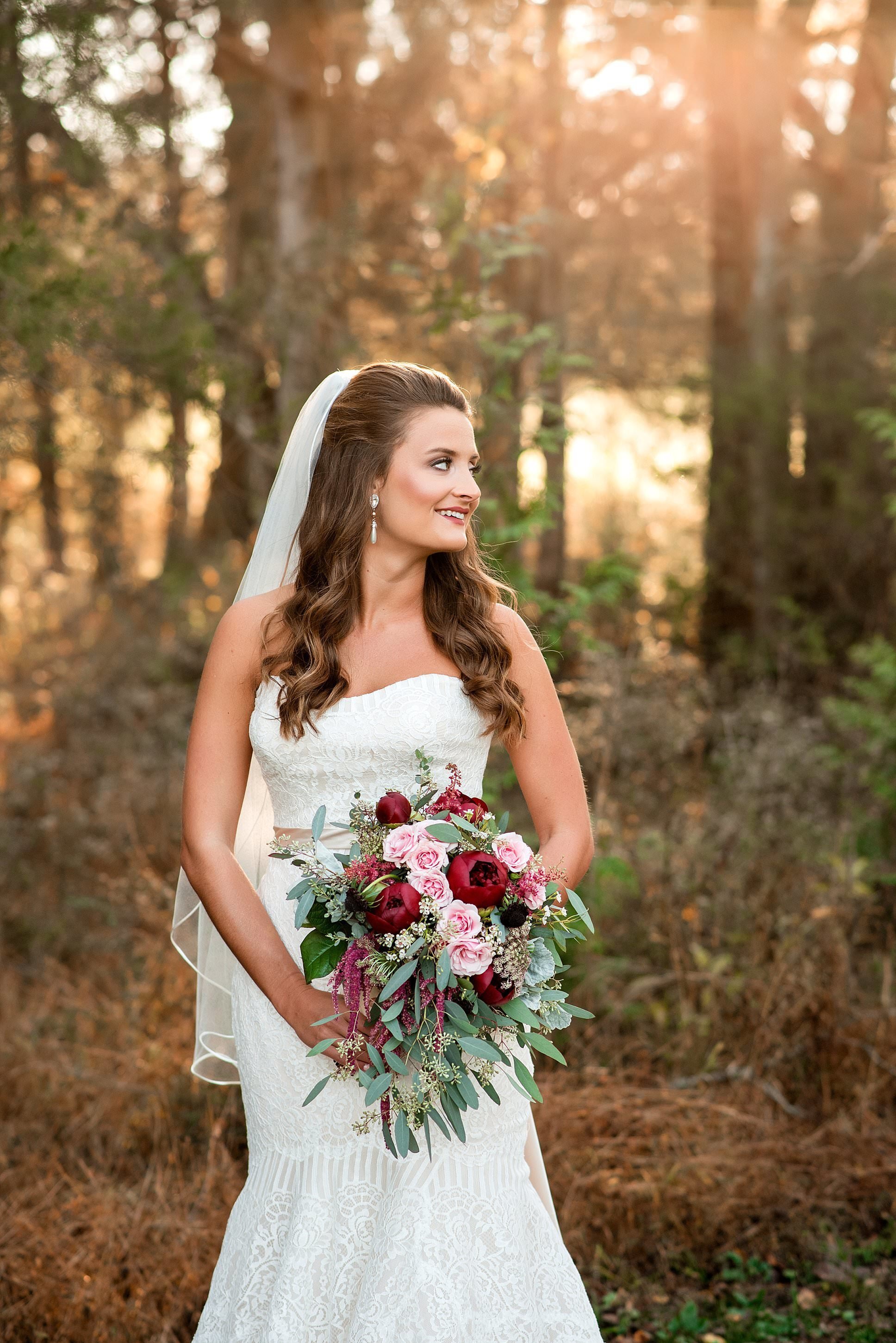 Bridal Portraits in the forest at Grace Valley Farm during golden hour wearing a sweetheart dress and holding a pink and burgundy bouquet