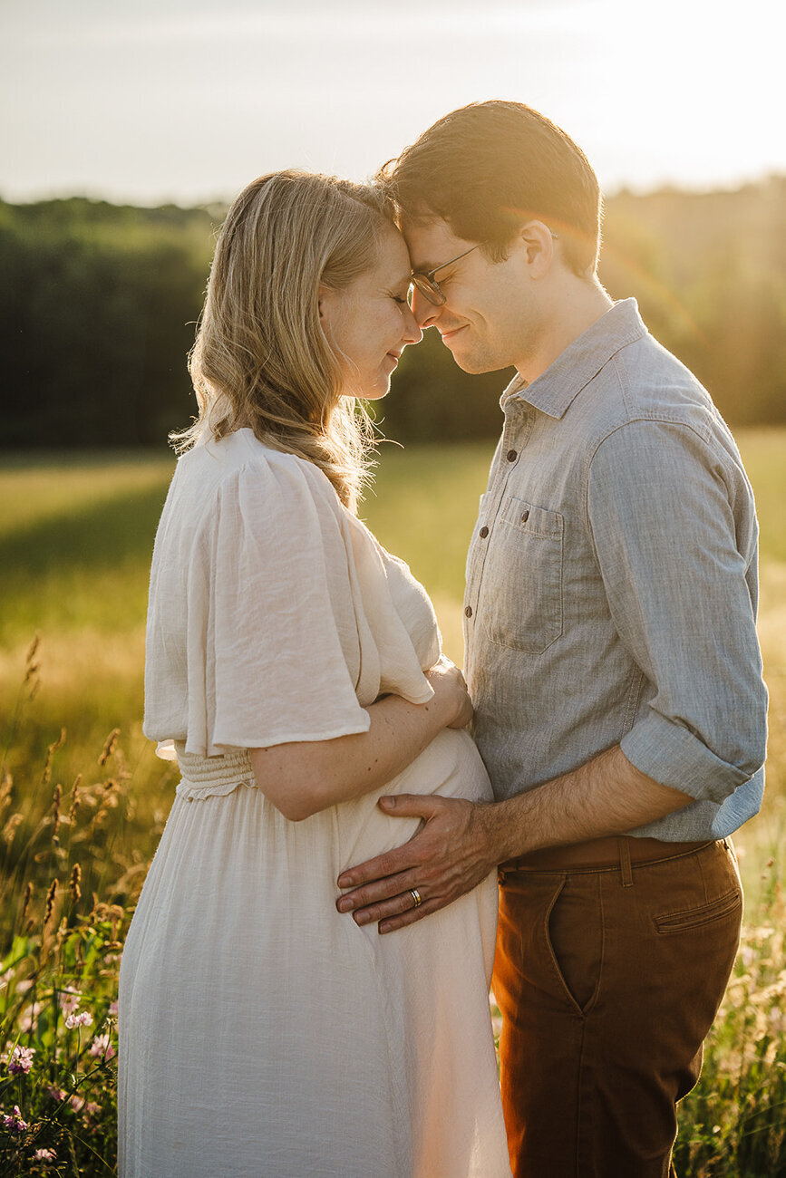 couple stand face to face for maternity photos at sunset in boston