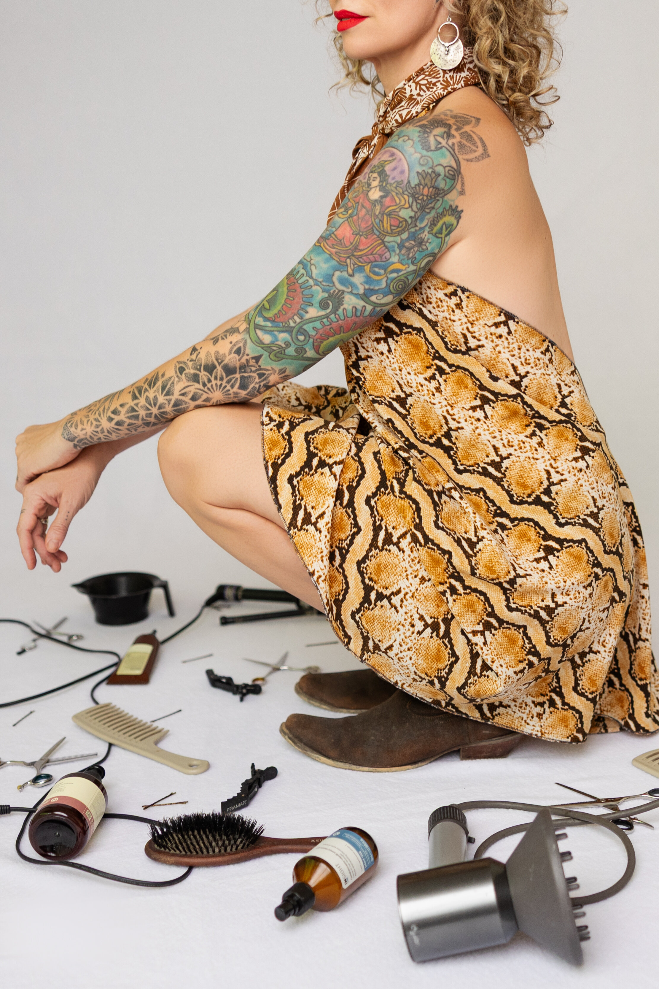 woman squats with hair supplies all around her in a branding photoshoot