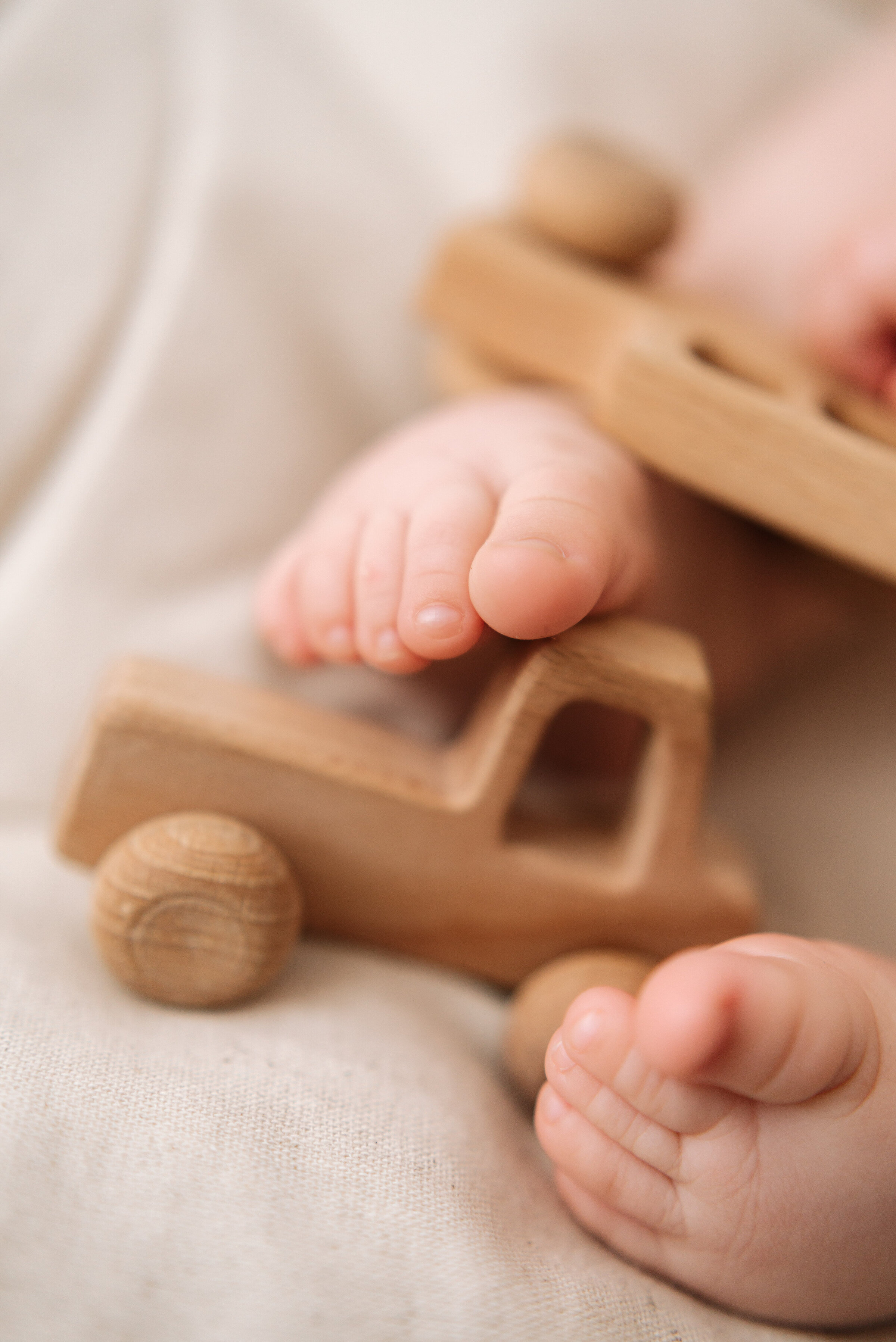 One year old feet with wooden cars at milestone photoshoot Billingshurst