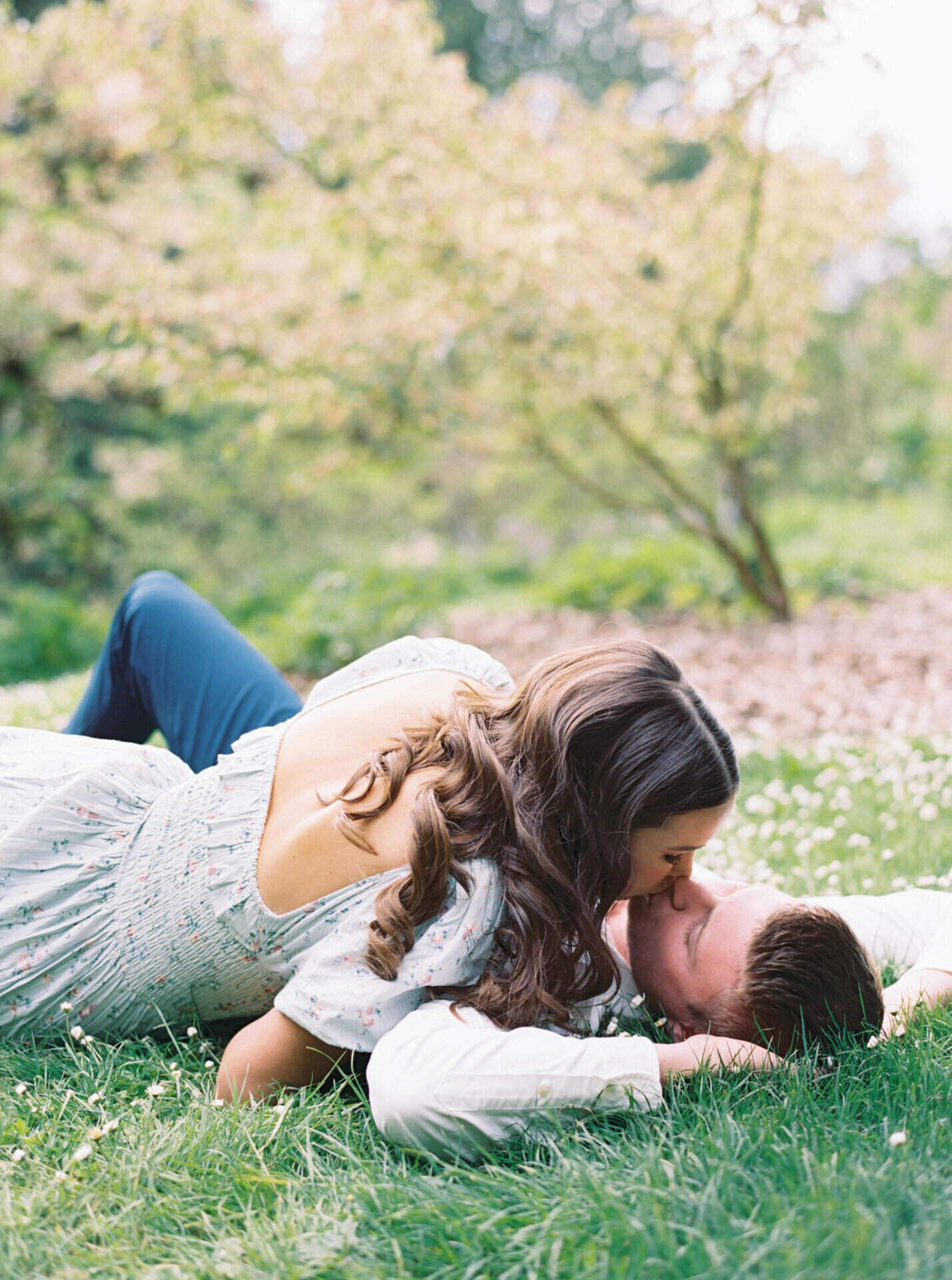 romantic couple laying in park grass kissing